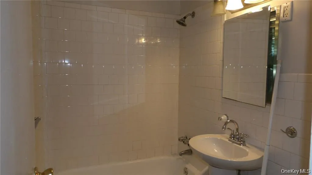 Bathroom featuring shower / bath combination, tile walls, and backsplash Bathroom featuring shower / bath combination, tile walls, and backsplash