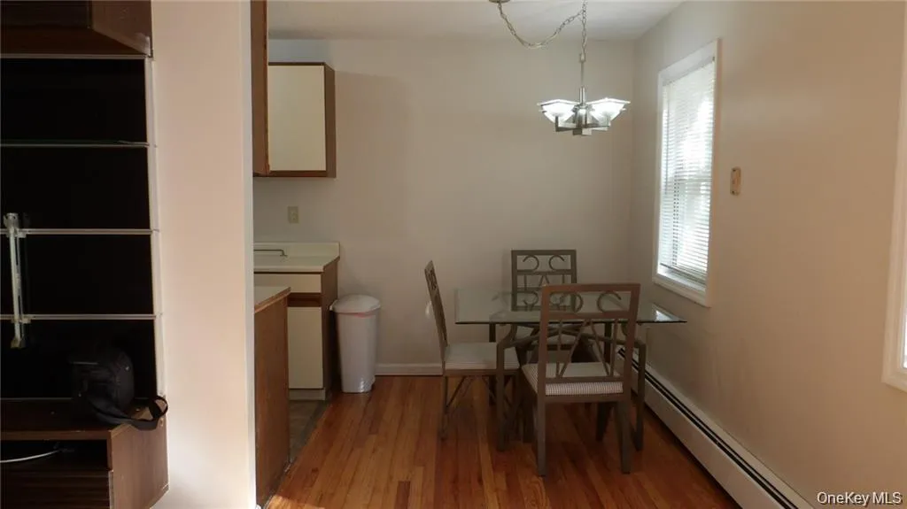 Dining space with light wood finished floors, baseboard heating, and a chandelier Dining space with light wood finished floors, baseboard heating, and a chandelier