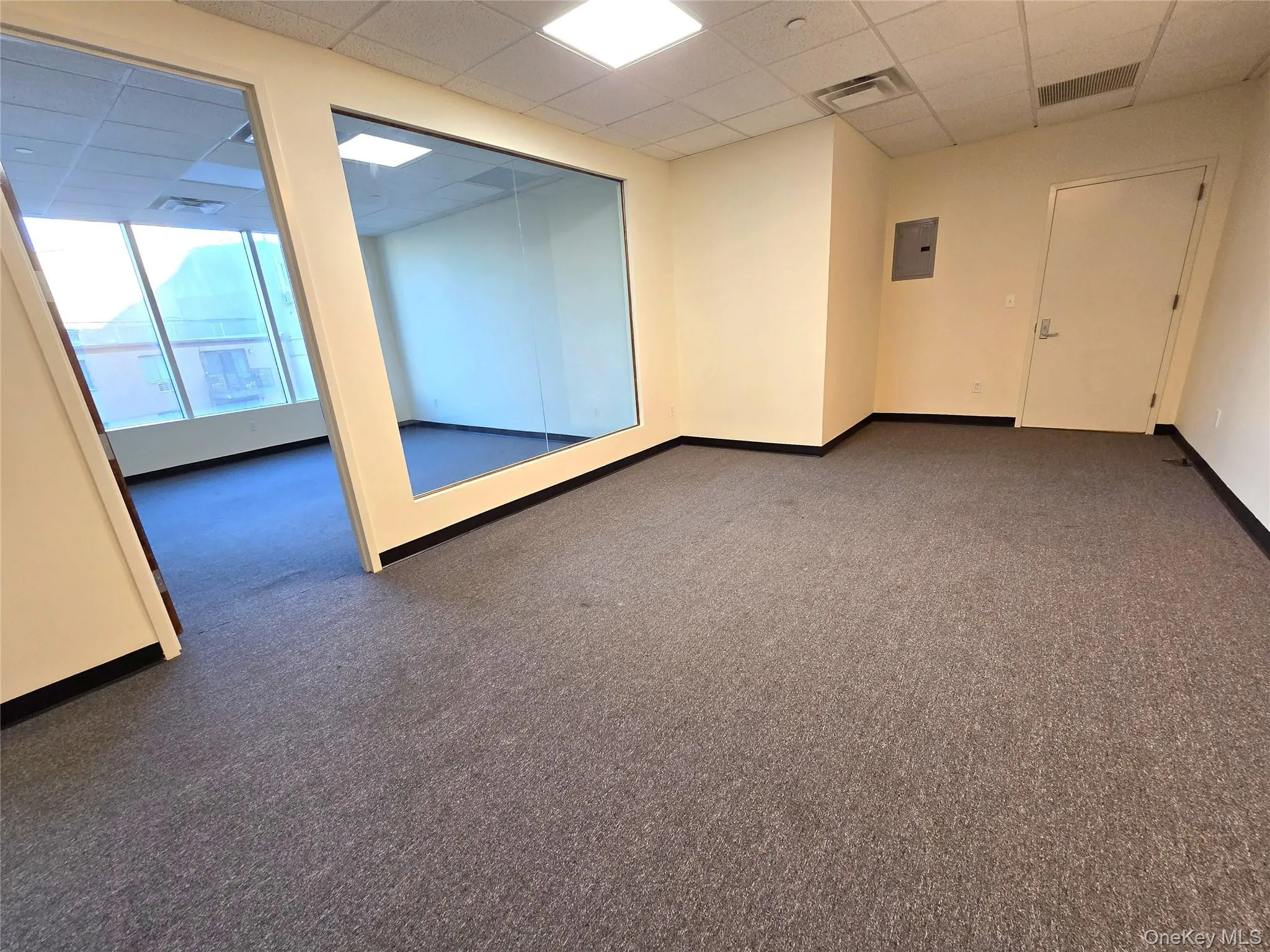 Unfurnished room featuring a drop ceiling, dark colored carpet, and electric panel Unfurnished room featuring a drop ceiling, dark colored carpet, and electric panel