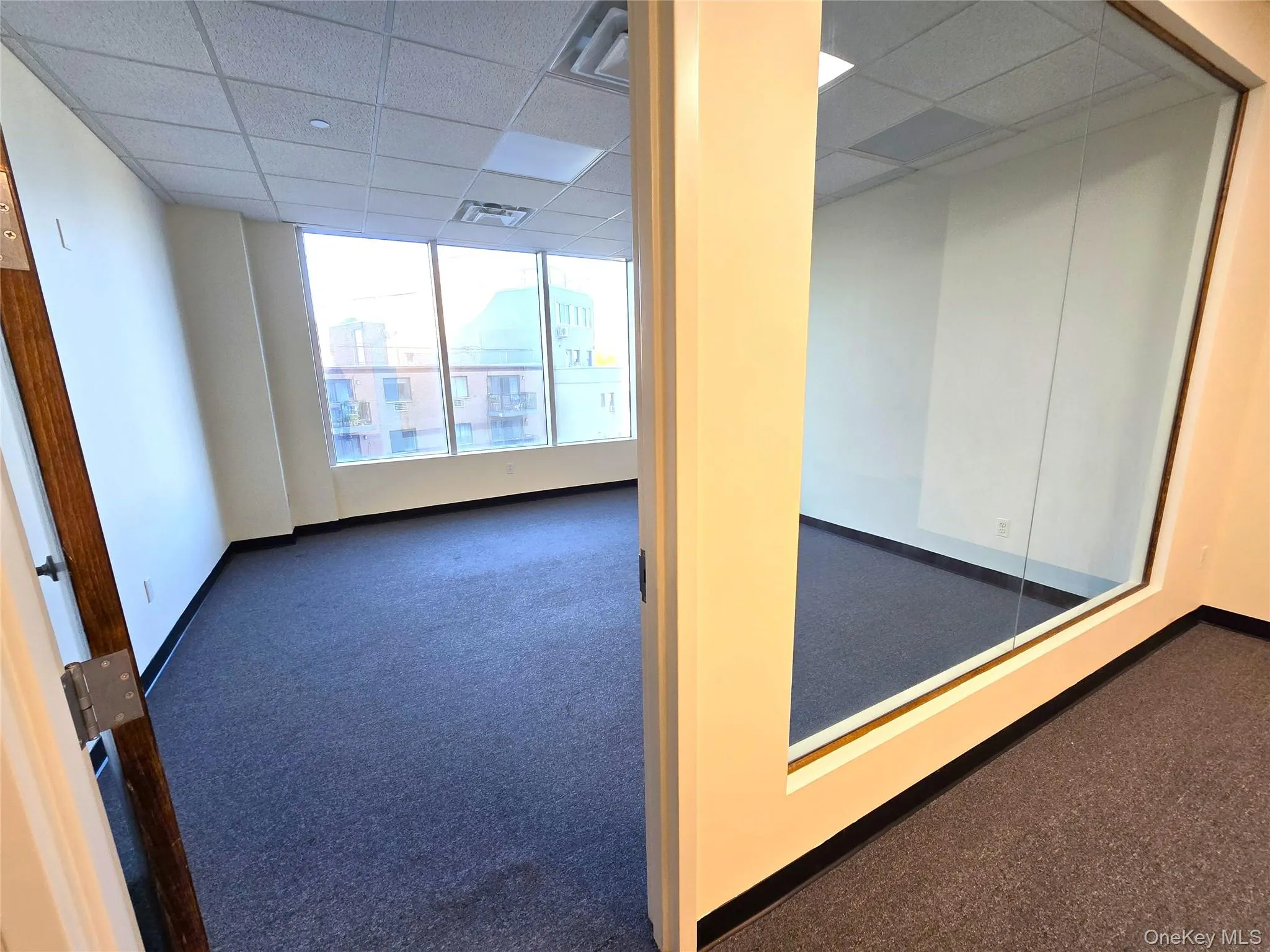 Empty room featuring dark colored carpet and a drop ceiling Empty room featuring dark colored carpet and a drop ceiling