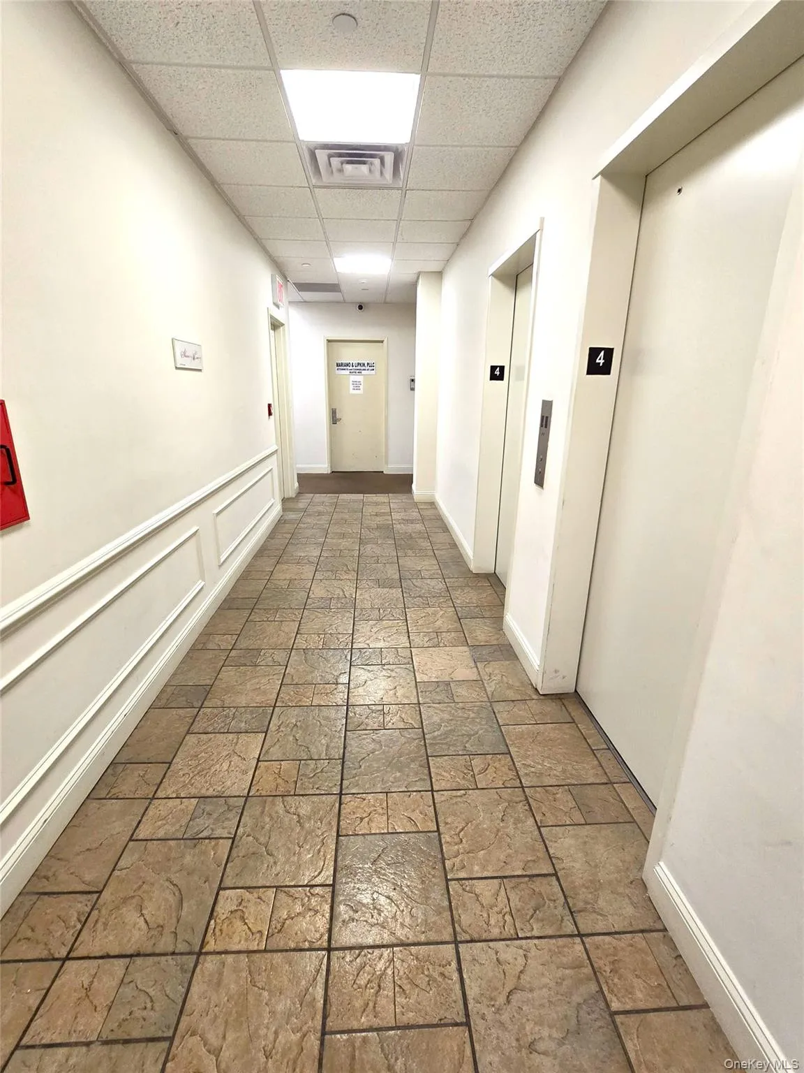 Hall featuring a paneled ceiling, elevator, and stone tile flooring Hall featuring a paneled ceiling, elevator, and stone tile flooring