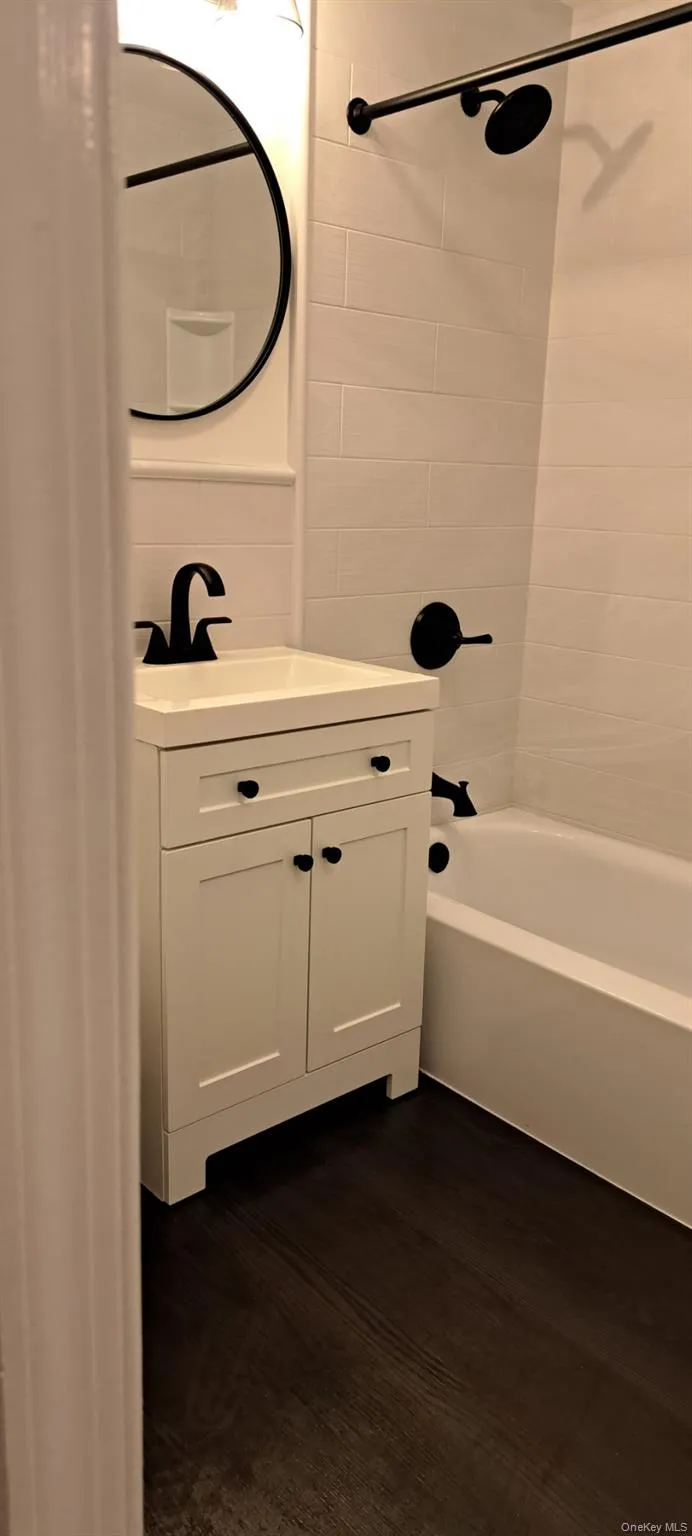 Bathroom with shower / washtub combination, vanity, and dark wood-style floors Bathroom with shower / washtub combination, vanity, and dark wood-style floors