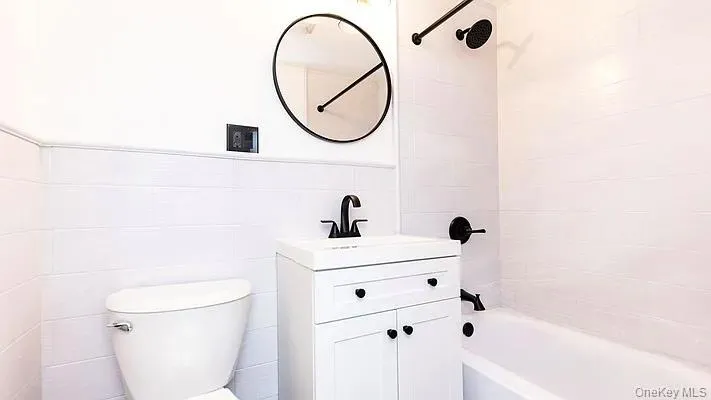 Full bath with bathtub / shower combination, vanity, and tile walls Full bath with bathtub / shower combination, vanity, and tile walls