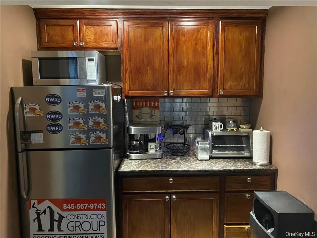 Kitchen with appliances with stainless steel finishes, tasteful backsplash, and dark stone countertops Kitchen with appliances with stainless steel finishes, tasteful backsplash, and dark stone countertops