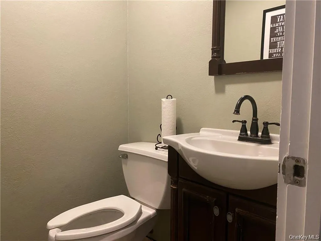 Half bathroom featuring a textured wall and vanity Half bathroom featuring a textured wall and vanity