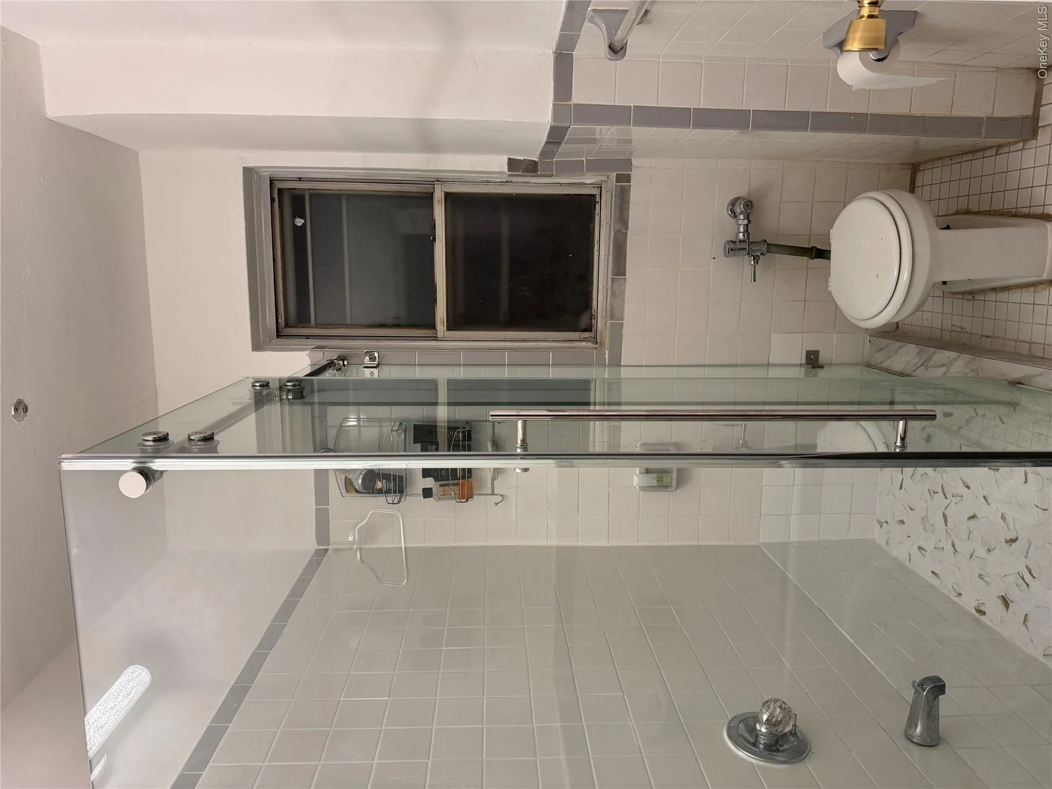 Full bathroom featuring tile walls, light tile patterned floors, a stall shower, and wainscoting Full bathroom featuring tile walls, light tile patterned floors, a stall shower, and wainscoting