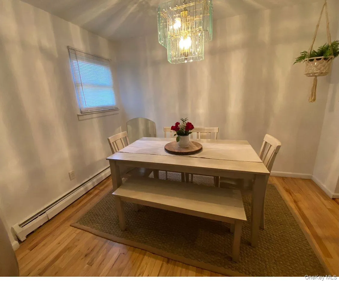 Dining room with a baseboard radiator, light wood-type flooring, and a chandelier Dining room with a baseboard radiator, light wood-type flooring, and a chandelier