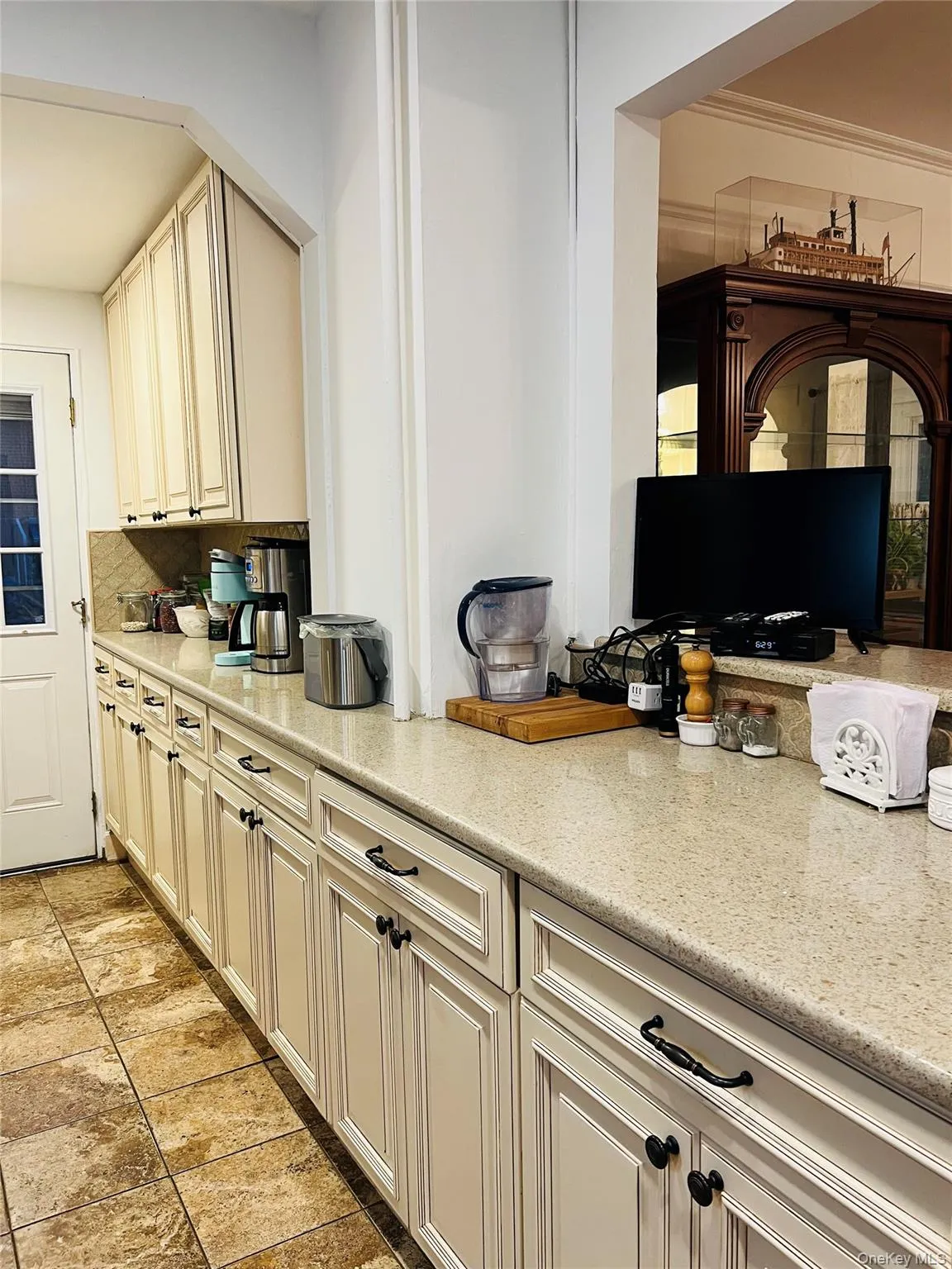 Kitchen featuring cream cabinets, light stone counters, and tasteful backsplash Kitchen featuring cream cabinets, light stone counters, and tasteful backsplash