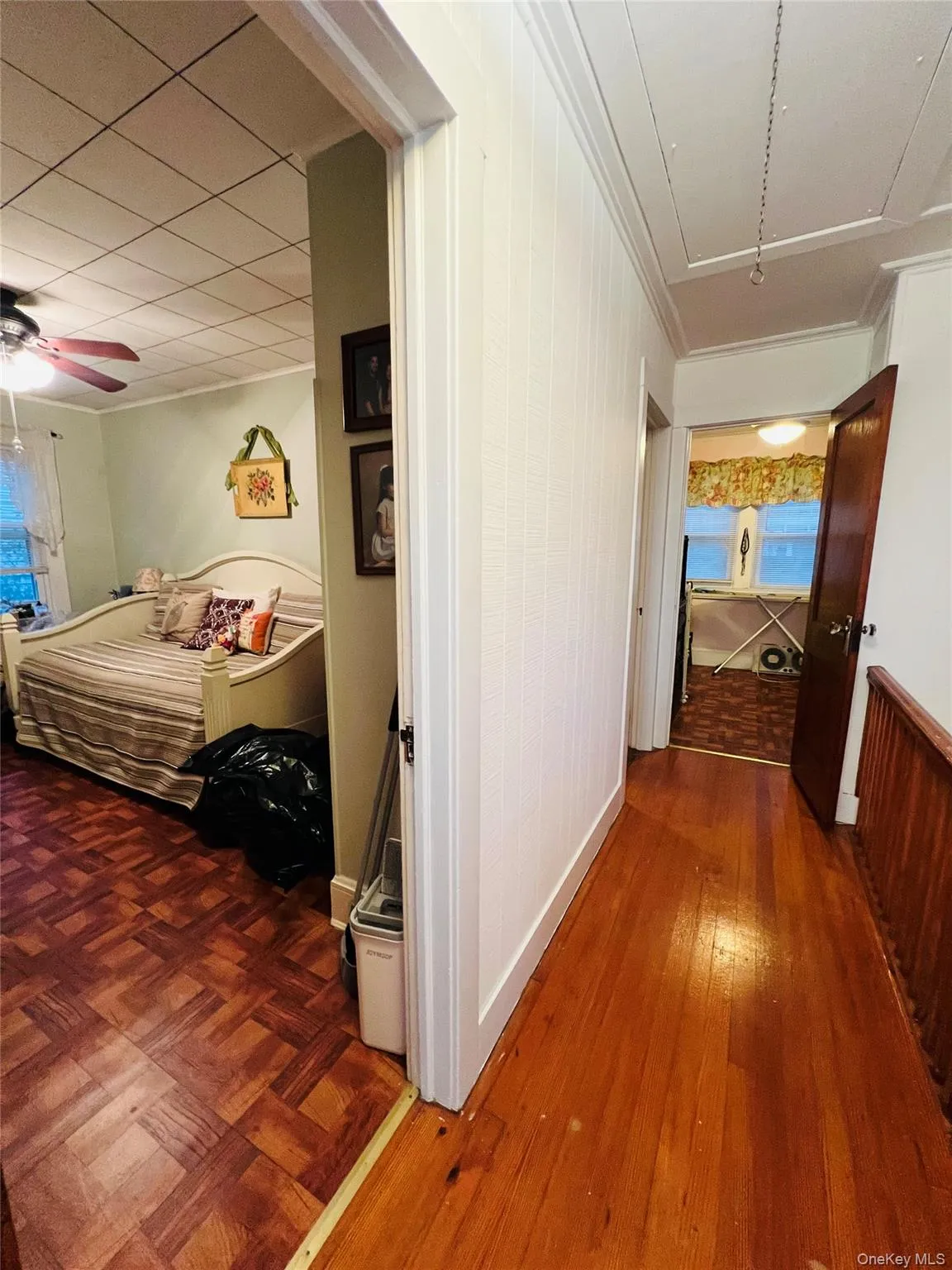 Hall featuring dark wood-type flooring, attic access, and wooden walls Hall featuring dark wood-type flooring, attic access, and wooden walls