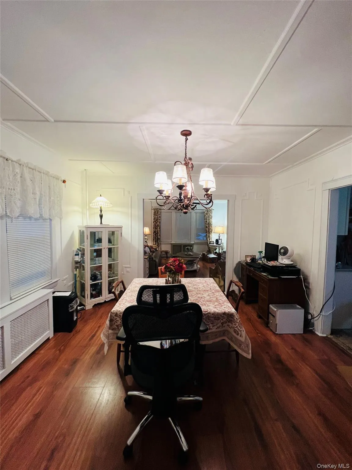 Dining room featuring radiator heating unit, dark wood finished floors, a chandelier, and a decorative wall Dining room featuring radiator heating unit, dark wood finished floors, a chandelier, and a decorative wall