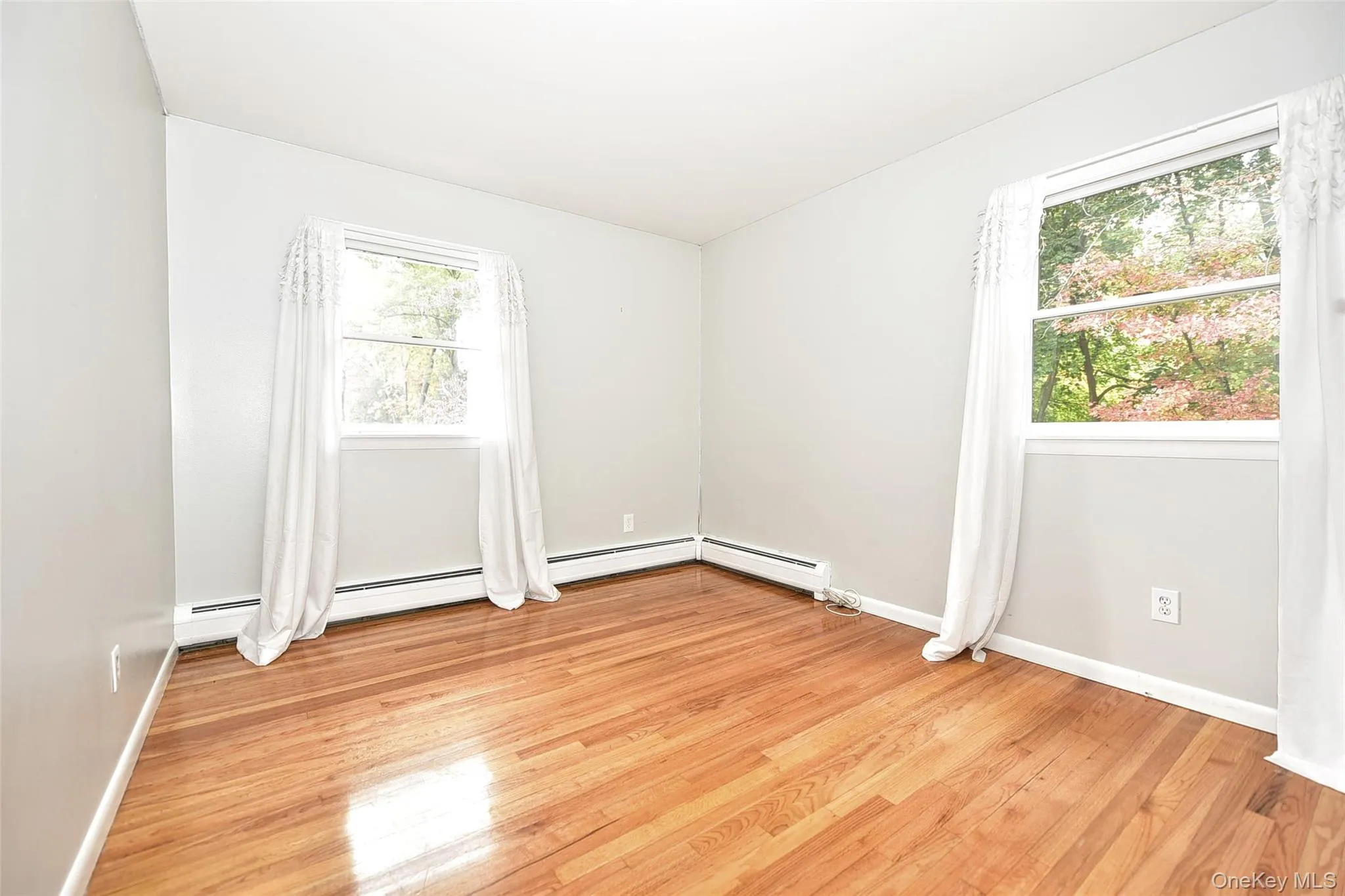 Spare room featuring light wood-style flooring and baseboard heating Spare room featuring light wood-style flooring and baseboard heating