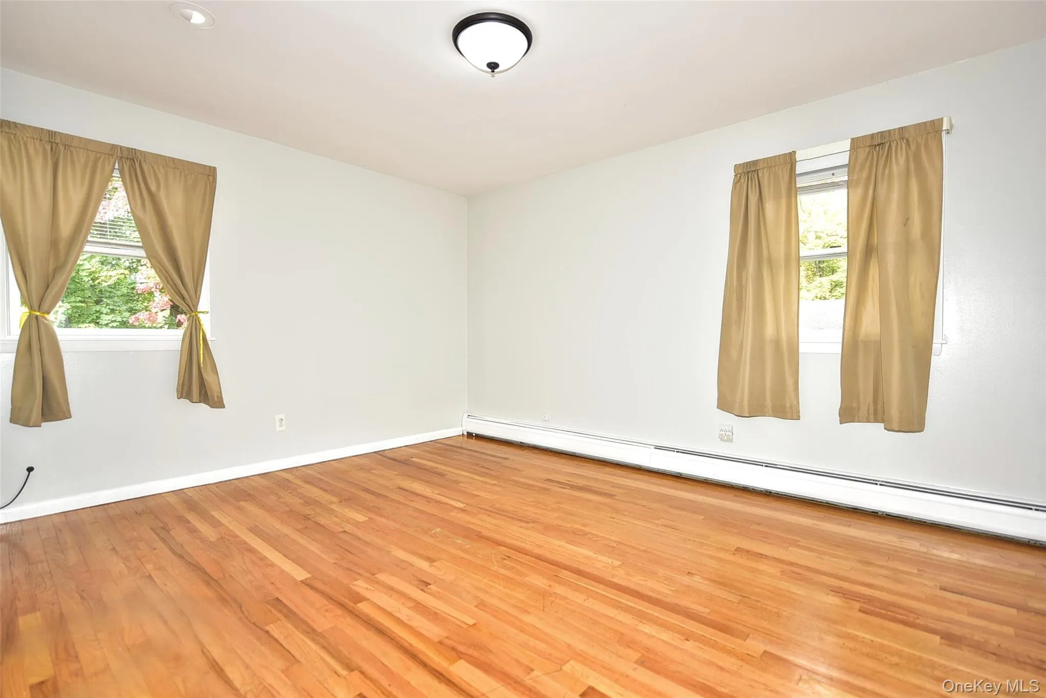 Unfurnished room featuring a baseboard radiator and light wood finished floors Unfurnished room featuring a baseboard radiator and light wood finished floors