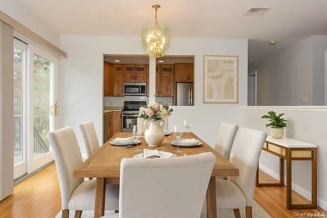Staged - Dining room with a chandelier and light wood-style floors Staged - Dining room with a chandelier and light wood-style floors