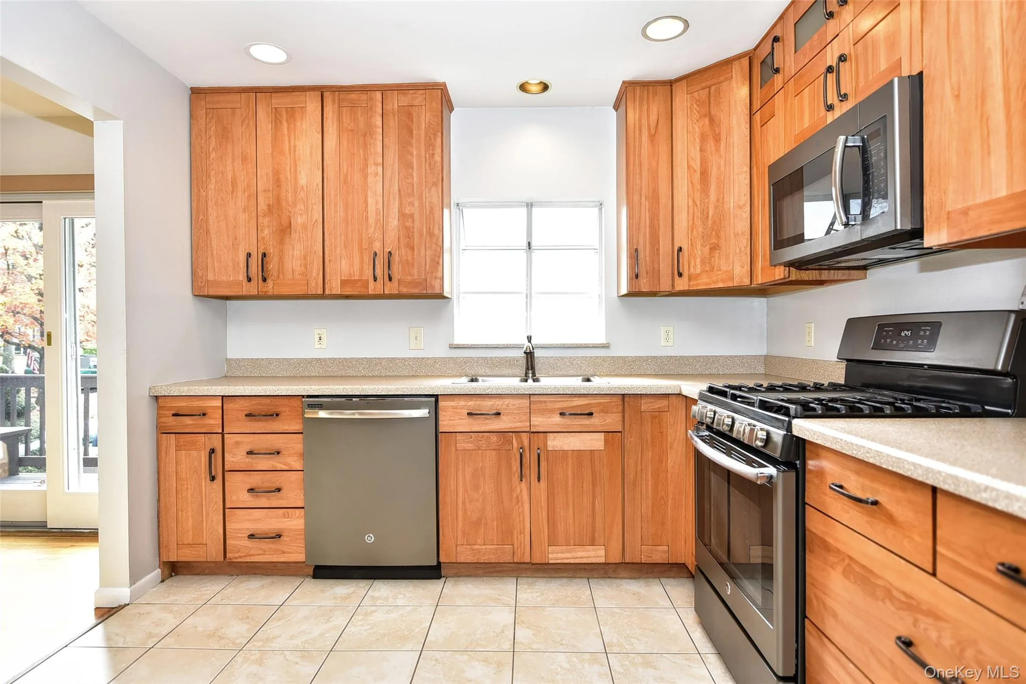Kitchen featuring stainless steel appliances, light stone counters, brown cabinets, light tile patterned flooring, and recessed lighting Kitchen featuring stainless steel appliances, light stone counters, brown cabinets, light tile patterned flooring, and recessed lighting