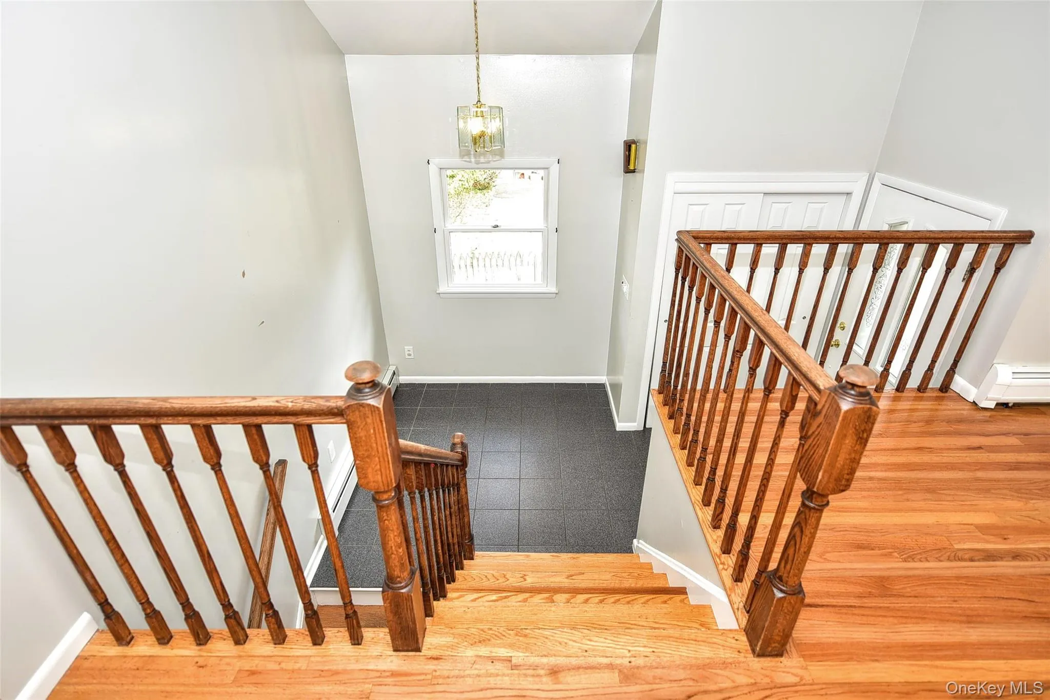 Stairway with wood finished floors, a chandelier, and a baseboard heating unit Stairway with wood finished floors, a chandelier, and a baseboard heating unit