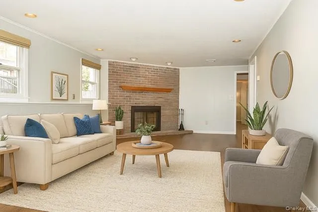 Staged - Living room with wood finished floors, a fireplace, recessed lighting, and crown molding Staged - Living room with wood finished floors, a fireplace, recessed lighting, and crown molding