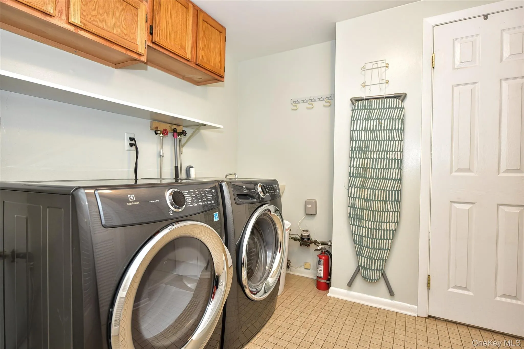 Laundry area featuring cabinet space, light tile patterned floors, and washing machine and clothes dryer Laundry area featuring cabinet space, light tile patterned floors, and washing machine and clothes dryer