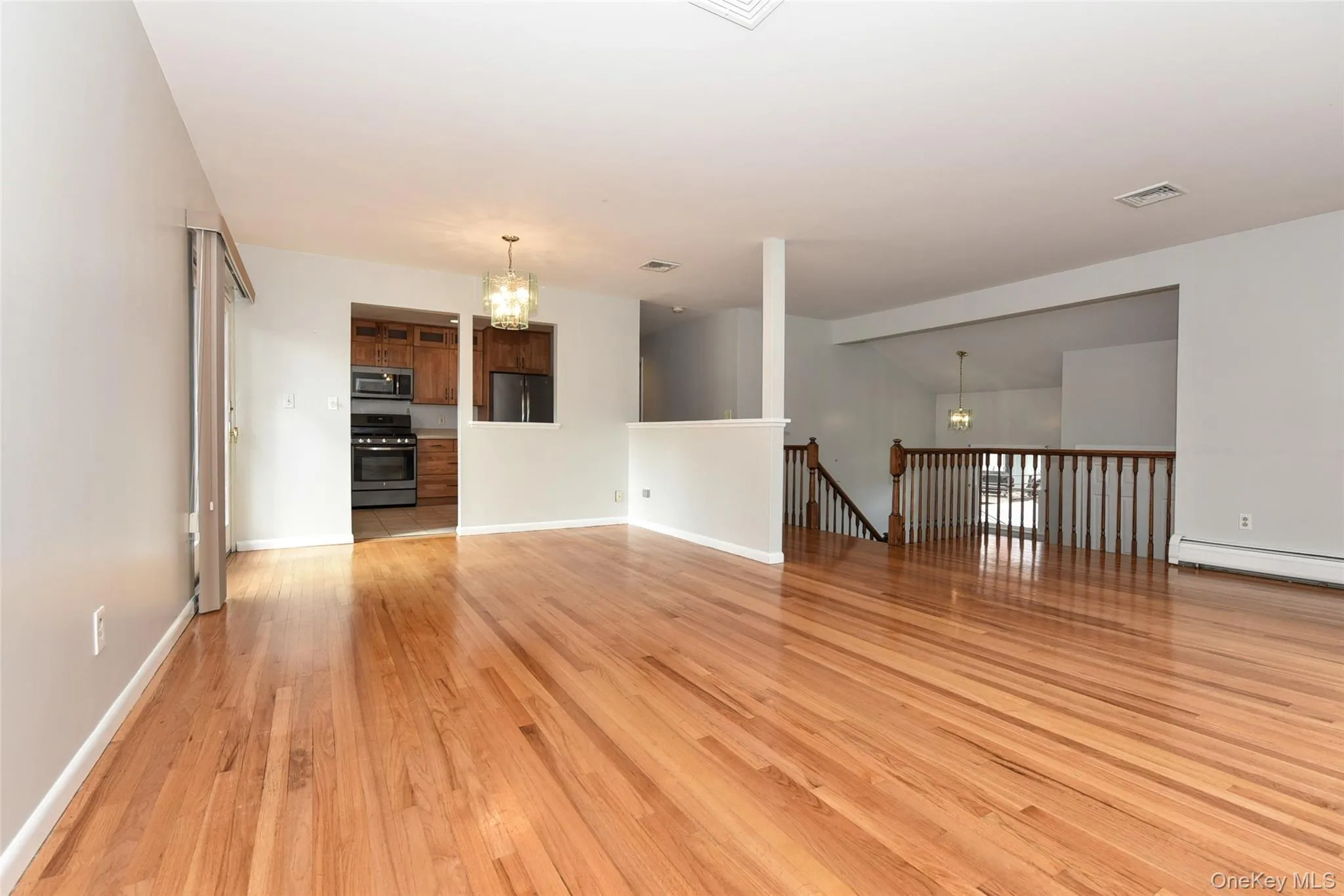 Unfurnished living room featuring a chandelier, light wood finished floors, and lofted ceiling Unfurnished living room featuring a chandelier, light wood finished floors, and lofted ceiling