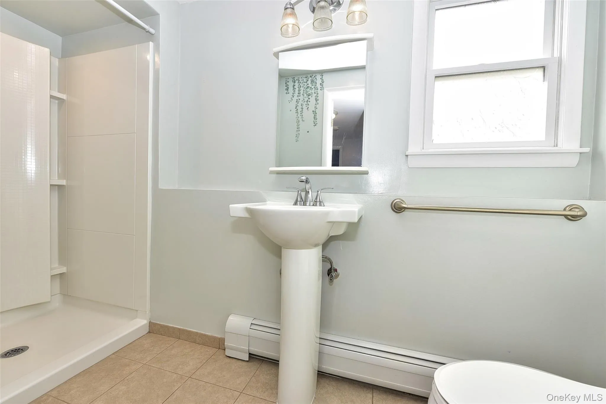 Bathroom featuring a shower stall, light tile patterned floors, baseboard heating, and a baseboard heating unit Bathroom featuring a shower stall, light tile patterned floors, baseboard heating, and a baseboard heating unit