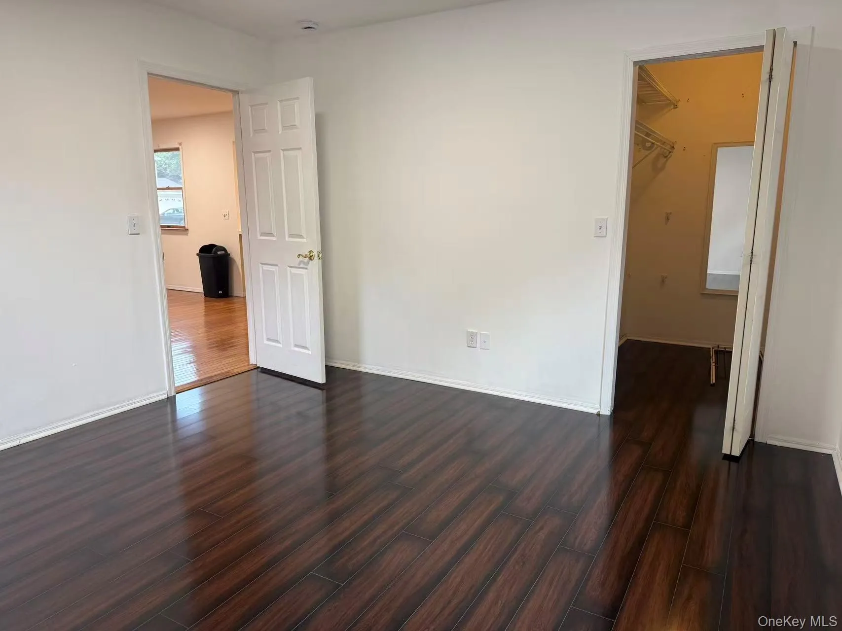 Big room with dark wood-style floors and baseboards Big room with dark wood-style floors and baseboards