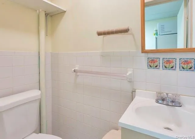 Half bath featuring tile walls, vanity, and a wainscoted wall Half bath featuring tile walls, vanity, and a wainscoted wall