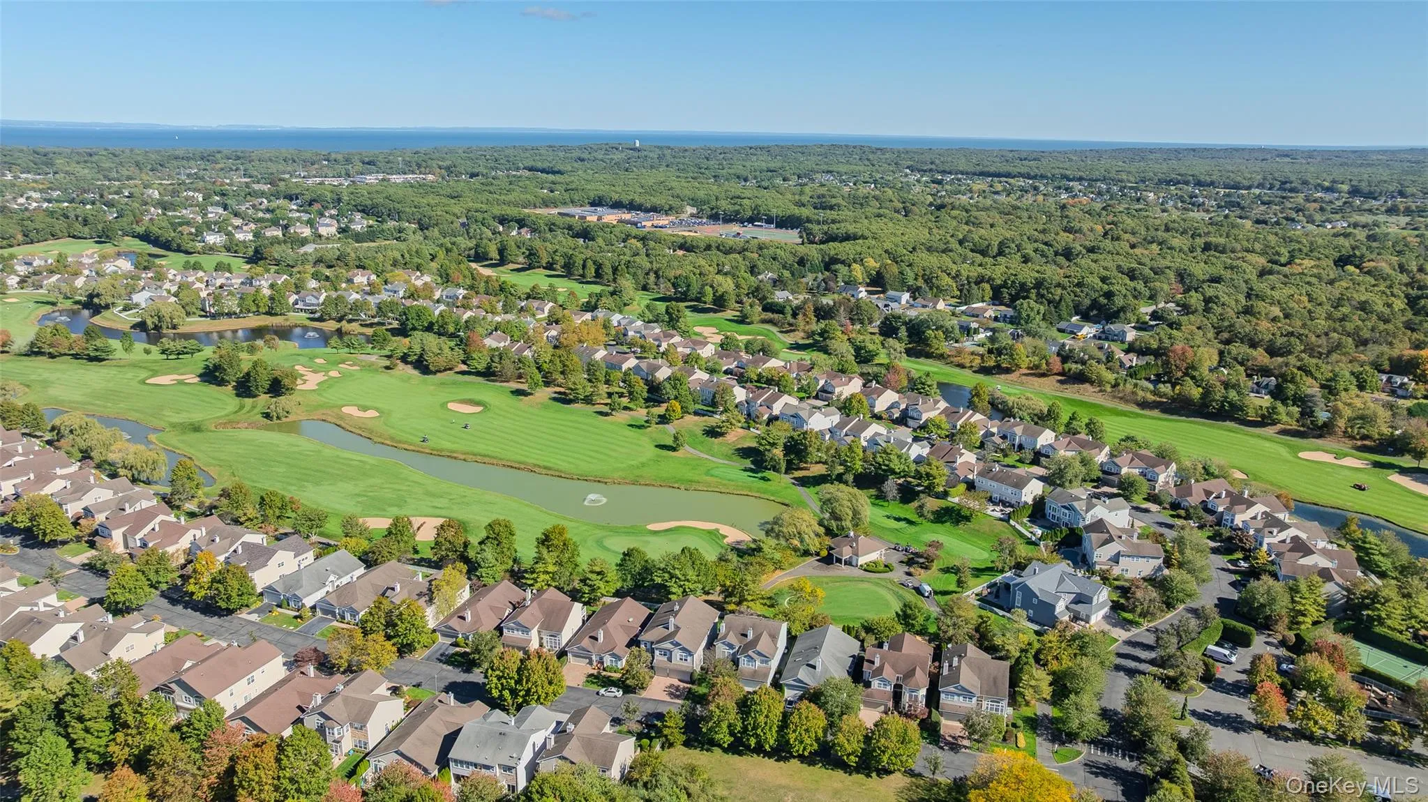 Aerial view of residential area with a nearby body of water and a local golf course Aerial view of residential area with a nearby body of water and a local golf course
