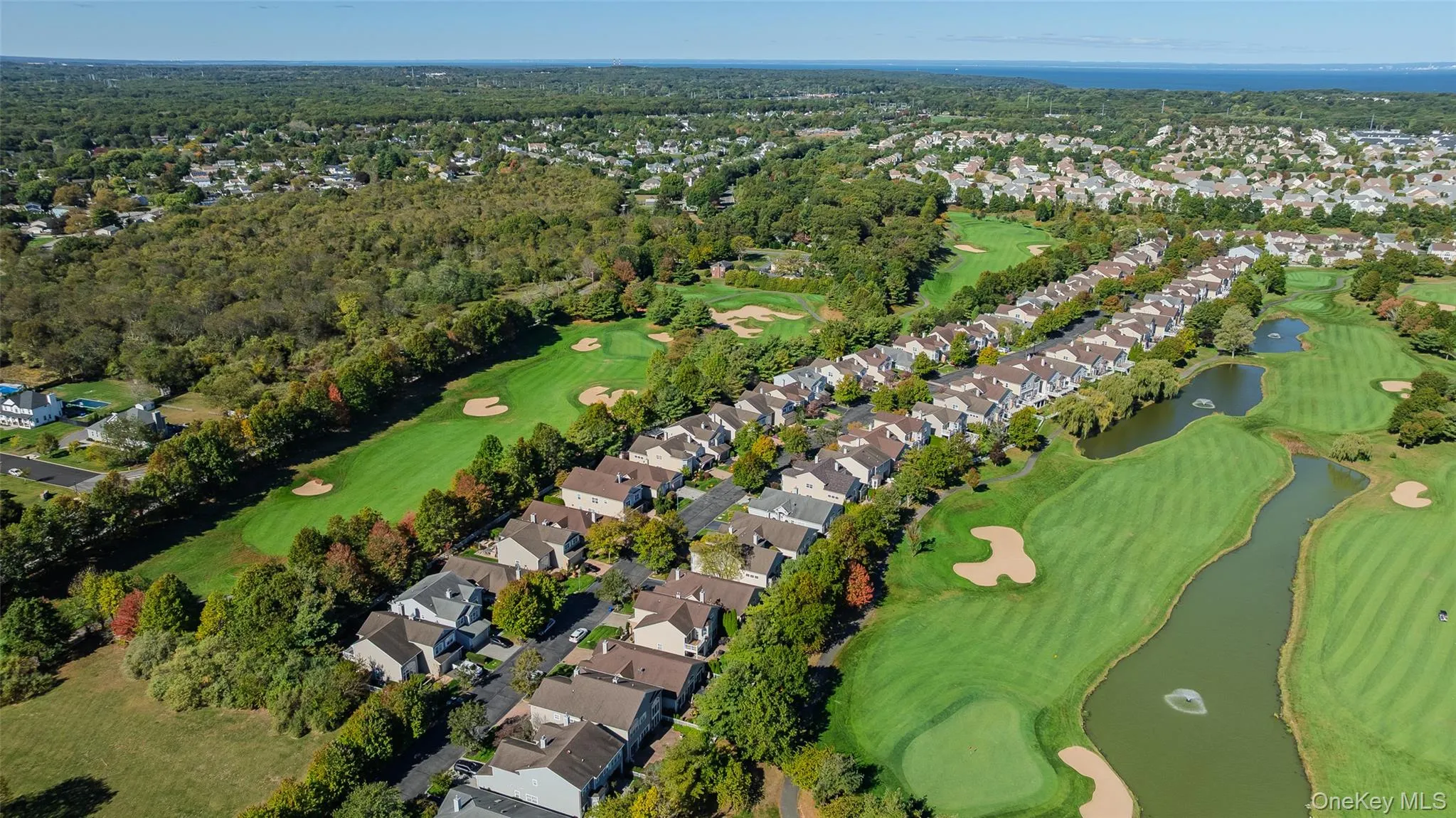 Aerial view of property's location featuring nearby suburban area, a nearby body of water, and a golf club Aerial view of property's location featuring nearby suburban area, a nearby body of water, and a golf club