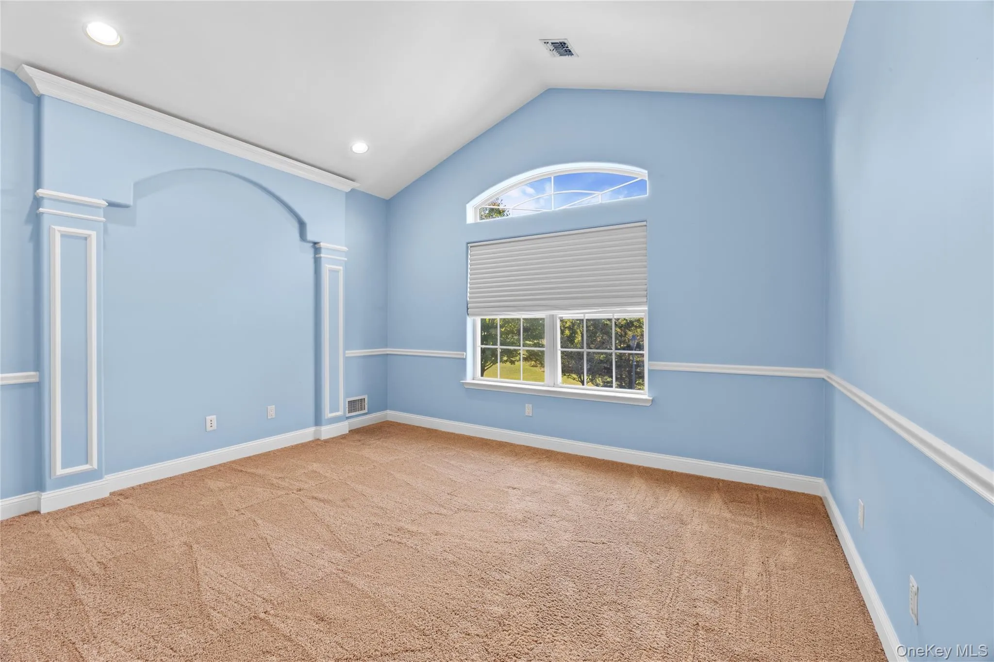 Spare room with lofted ceiling, light carpet, recessed lighting, and decorative columns Spare room with lofted ceiling, light carpet, recessed lighting, and decorative columns