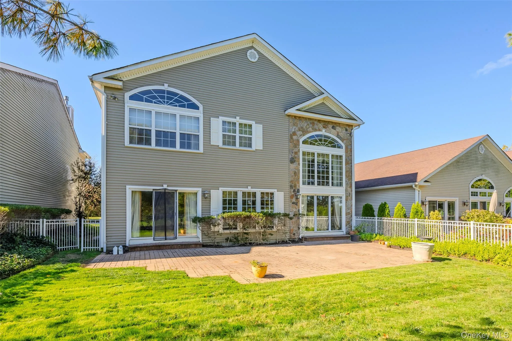 Back of house with a fenced backyard, stone siding, and a patio Back of house with a fenced backyard, stone siding, and a patio