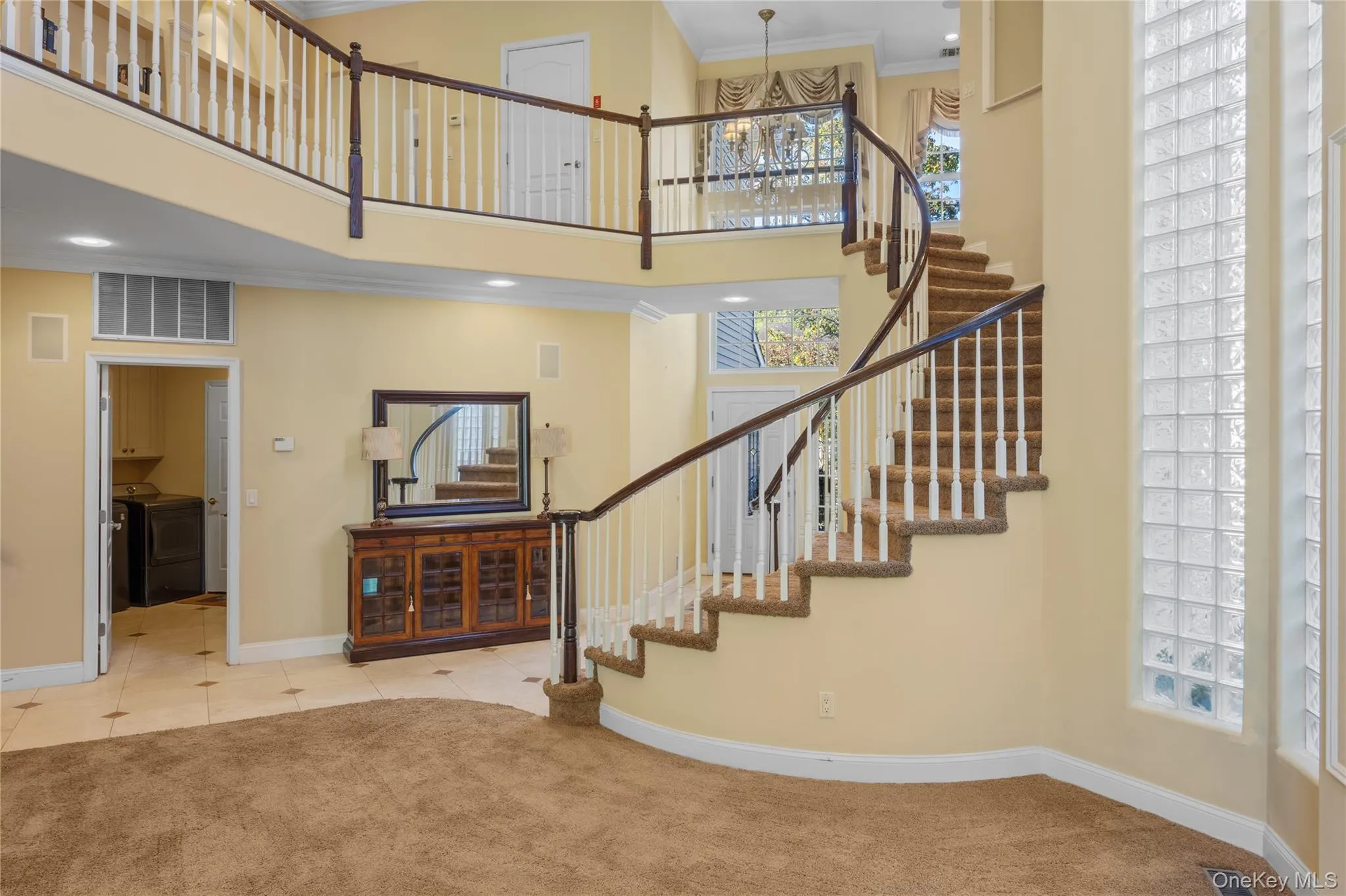 Stairway with ornamental molding, carpet, a towering ceiling, a chandelier, and tile patterned flooring Stairway with ornamental molding, carpet, a towering ceiling, a chandelier, and tile patterned flooring