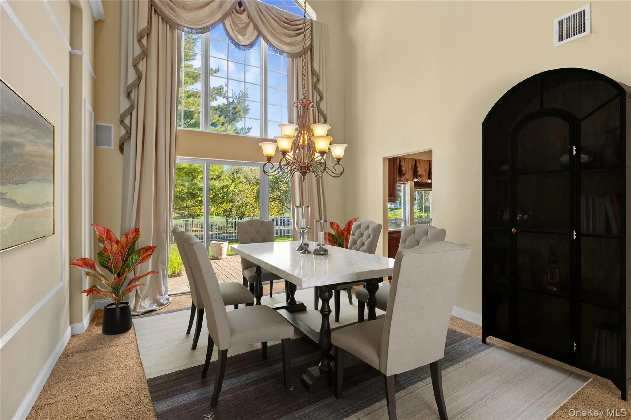 Dining room with carpet, a high ceiling, and a chandelier Dining room with carpet, a high ceiling, and a chandelier