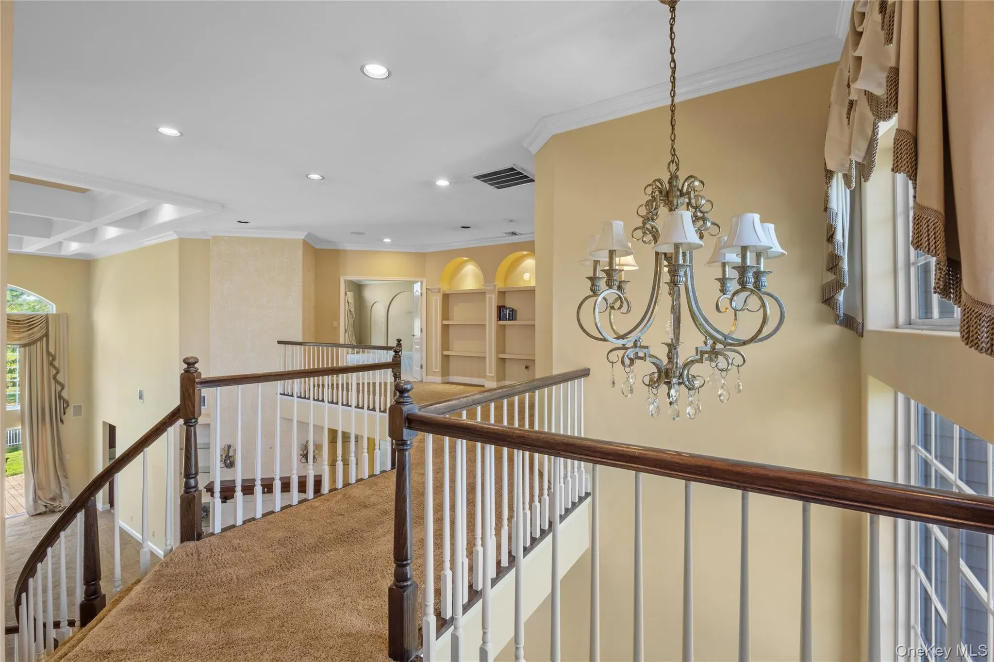 Hallway with a chandelier, an upstairs landing, ornamental molding, recessed lighting, and carpet floors Hallway with a chandelier, an upstairs landing, ornamental molding, recessed lighting, and carpet floors