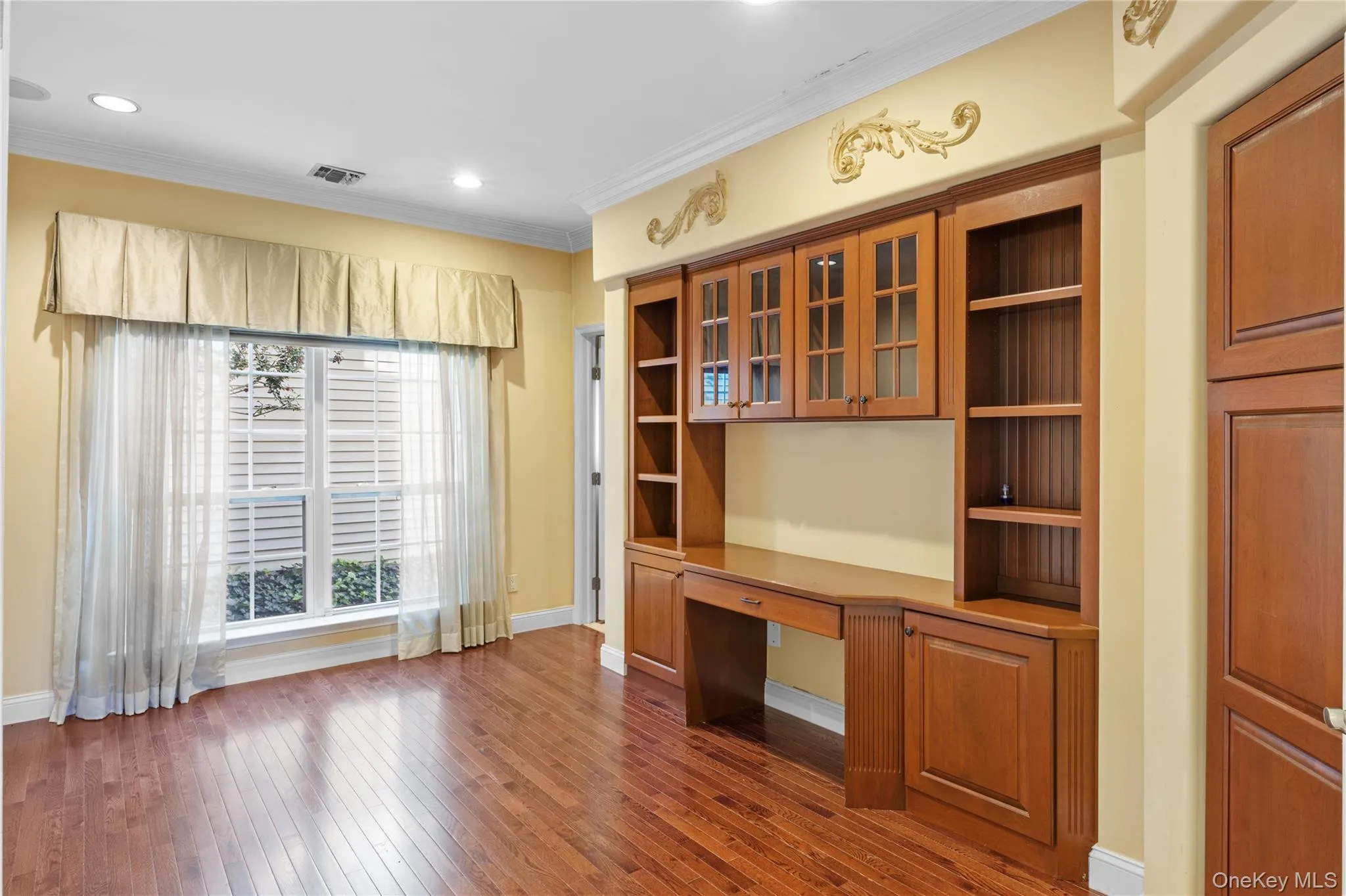 Unfurnished office featuring built in study area, dark wood-type flooring, crown molding, and recessed lighting Unfurnished office featuring built in study area, dark wood-type flooring, crown molding, and recessed lighting