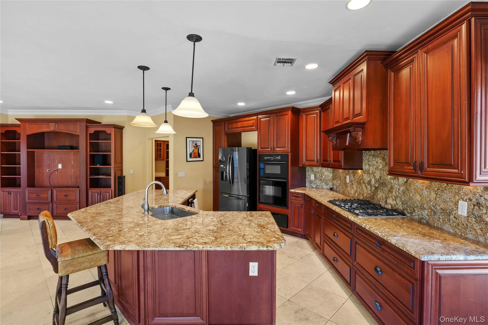Kitchen with backsplash, a breakfast bar area, hanging light fixtures, recessed lighting, and light stone counters Kitchen with backsplash, a breakfast bar area, hanging light fixtures, recessed lighting, and light stone counters