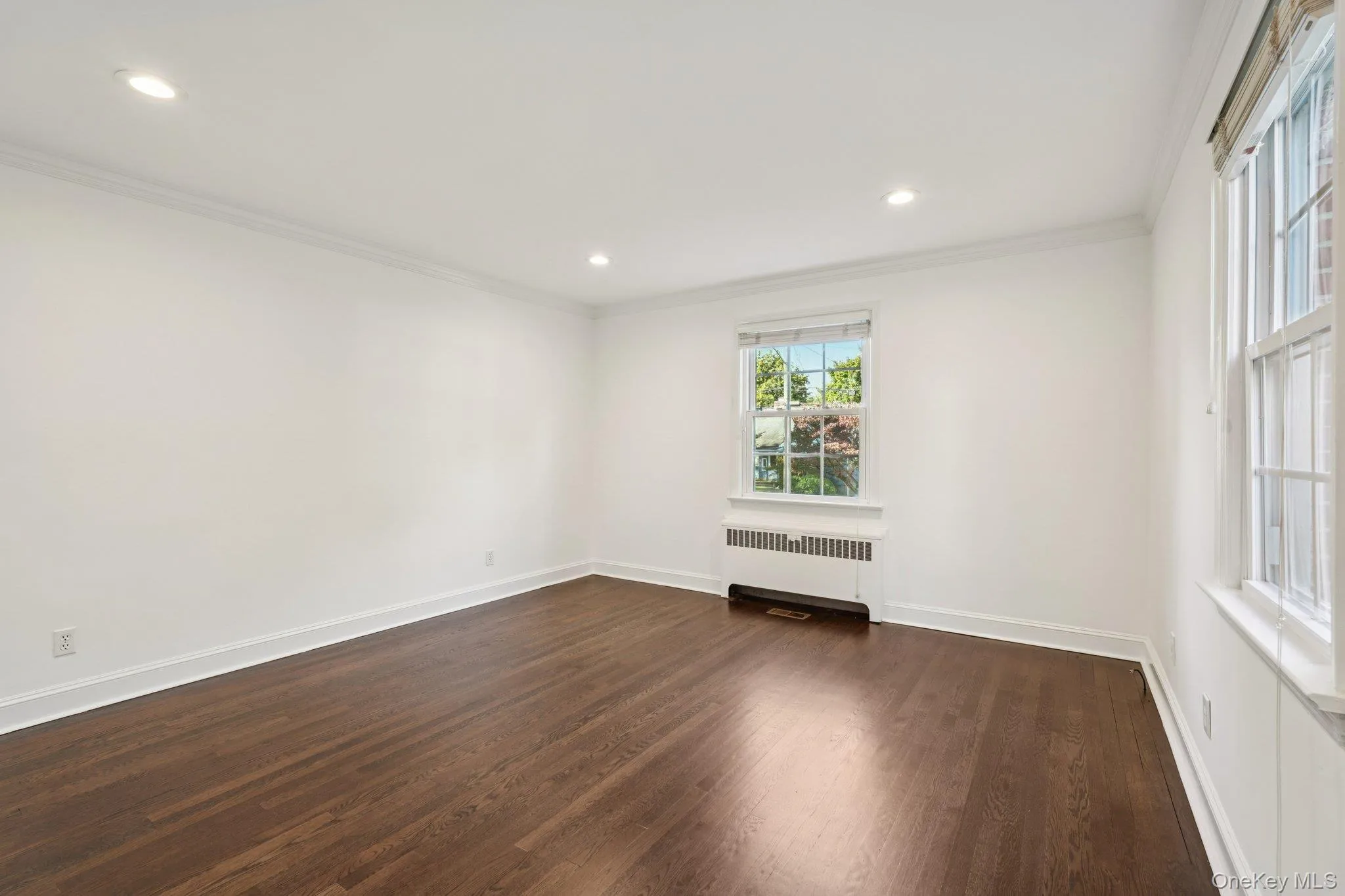 Unfurnished room with radiator, ornamental molding, dark wood-type flooring, and recessed lighting Unfurnished room with radiator, ornamental molding, dark wood-type flooring, and recessed lighting