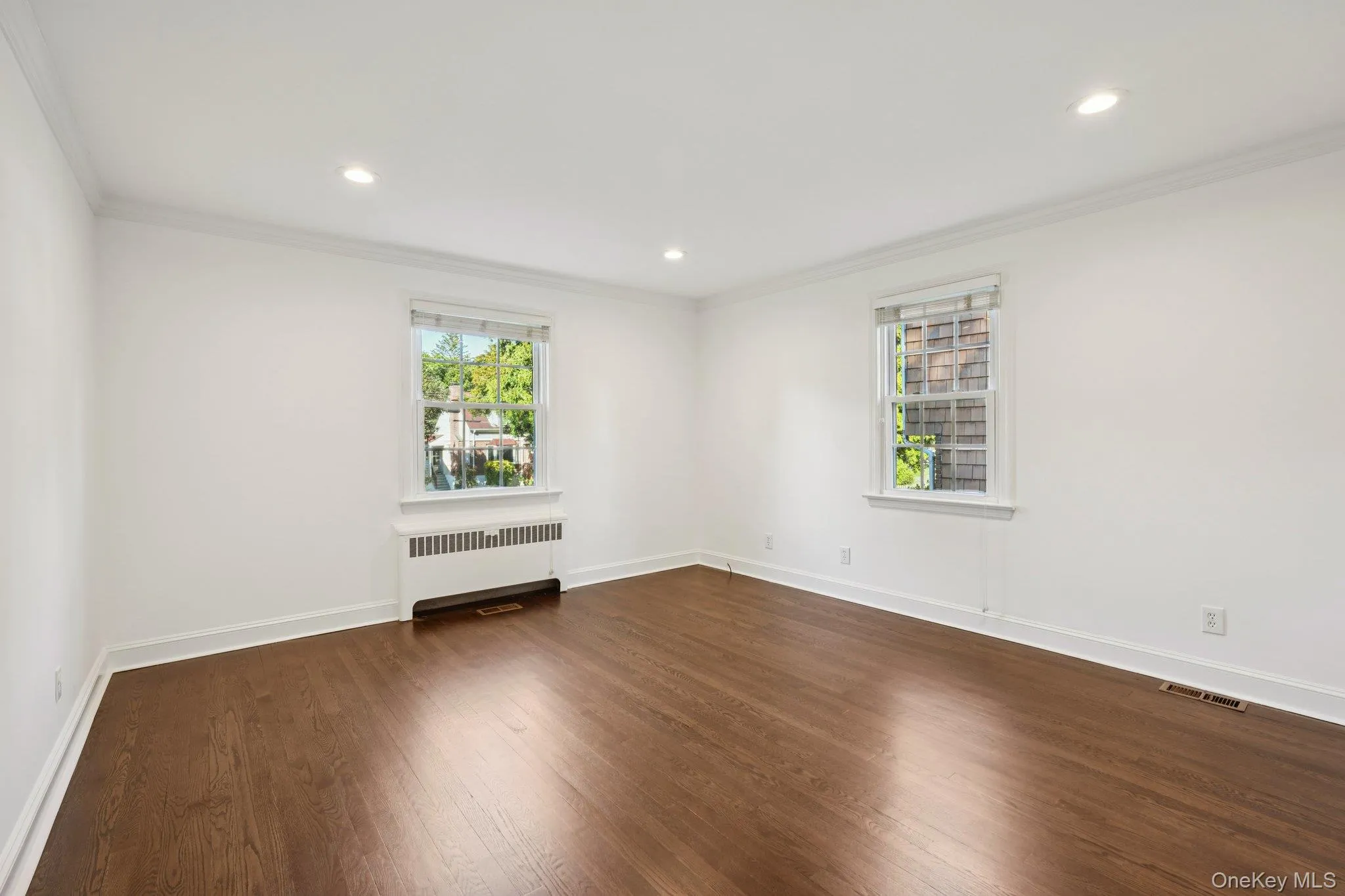 Spare room with radiator, ornamental molding, dark wood finished floors, and recessed lighting Spare room with radiator, ornamental molding, dark wood finished floors, and recessed lighting