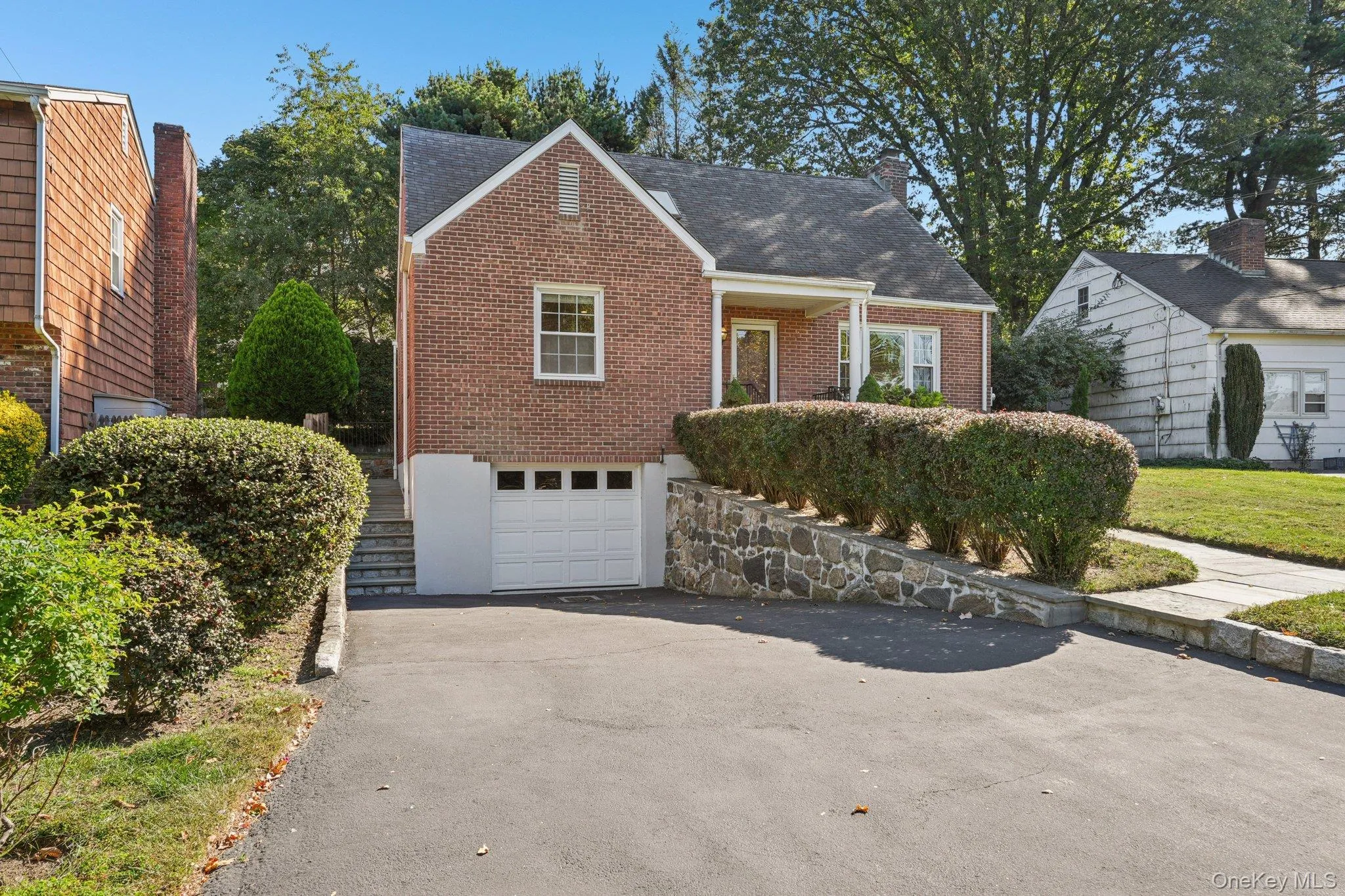 View of front of home featuring asphalt driveway, an attached garage, brick siding, covered porch, and stairs View of front of home featuring asphalt driveway, an attached garage, brick siding, covered porch, and stairs