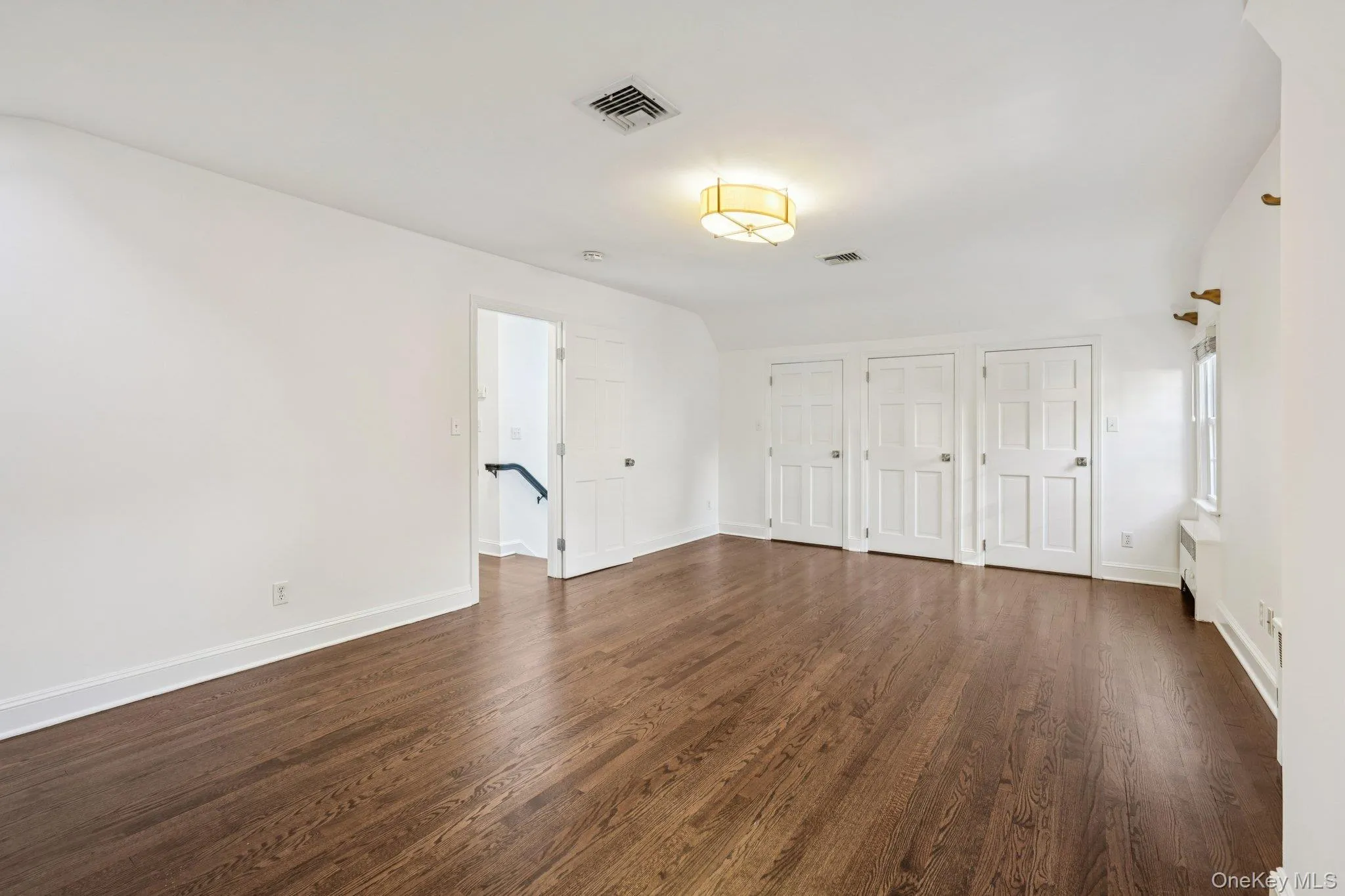 Unfurnished bedroom featuring multiple closets and dark wood-style floors Unfurnished bedroom featuring multiple closets and dark wood-style floors