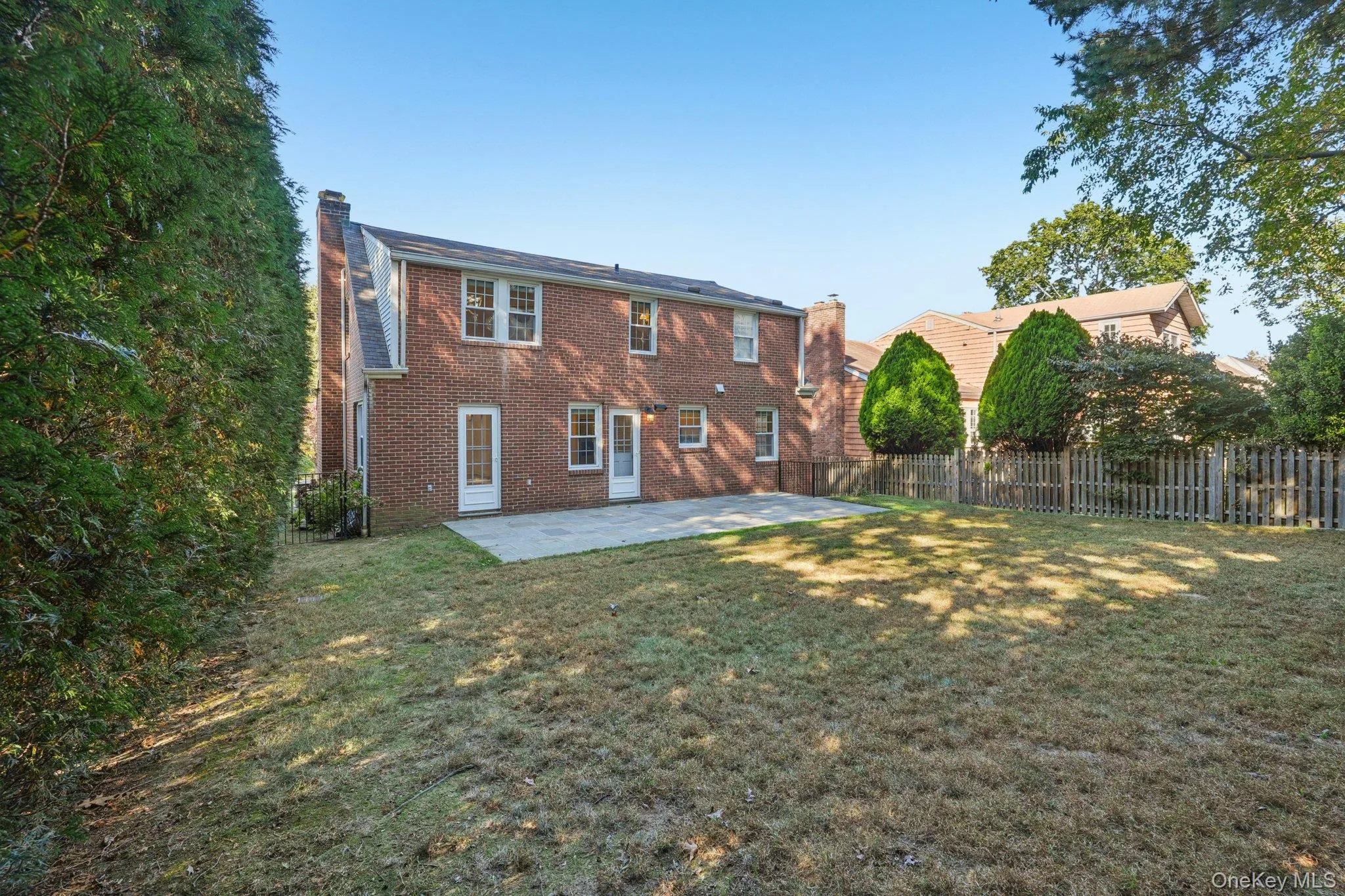 Back of house featuring a chimney, a patio area, brick siding, and a fenced backyard Back of house featuring a chimney, a patio area, brick siding, and a fenced backyard