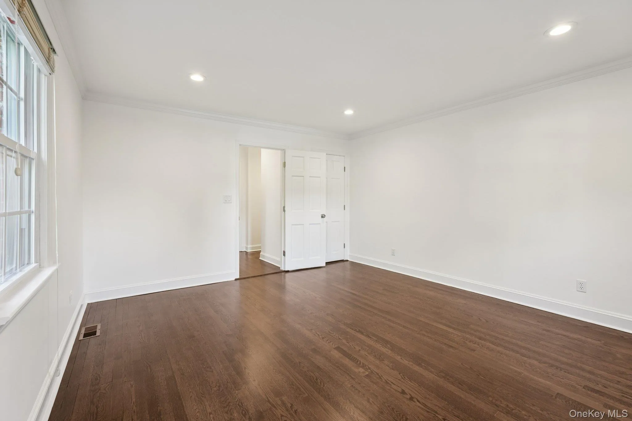 Unfurnished bedroom with crown molding, dark wood-style floors, and recessed lighting Unfurnished bedroom with crown molding, dark wood-style floors, and recessed lighting