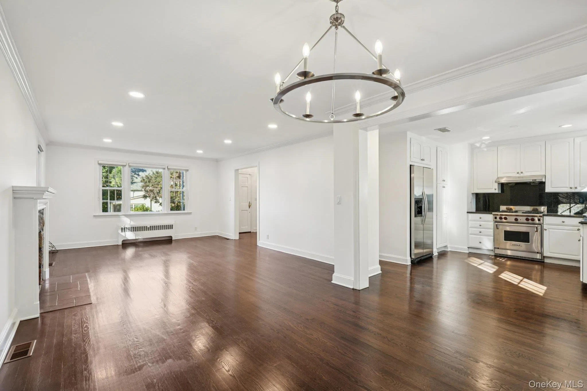Unfurnished living room featuring crown molding, dark wood-style flooring, recessed lighting, a chandelier, and a fireplace Unfurnished living room featuring crown molding, dark wood-style flooring, recessed lighting, a chandelier, and a fireplace