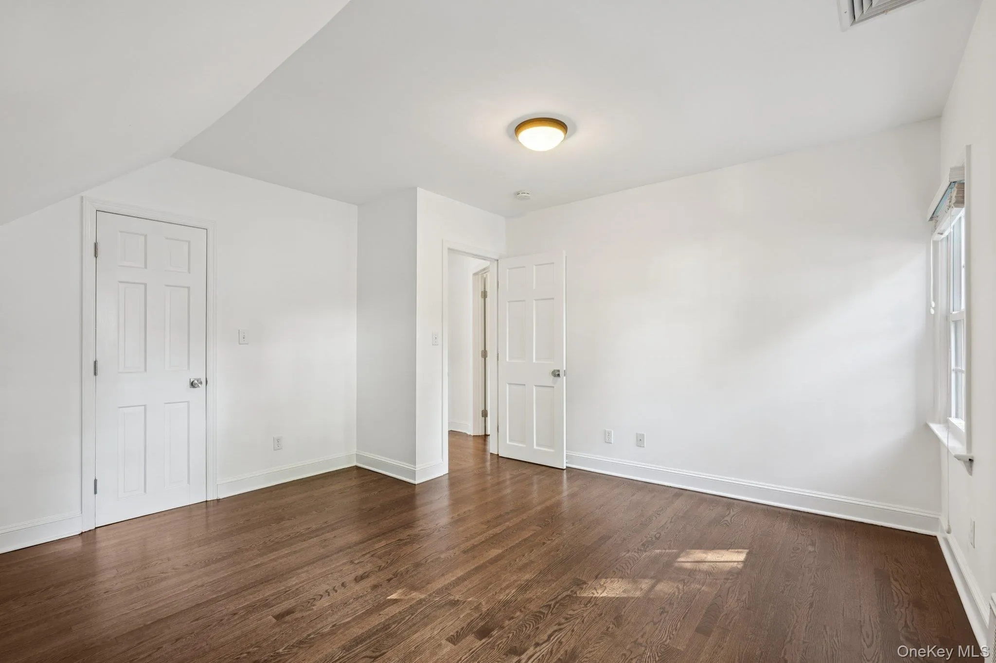 Unfurnished bedroom with dark wood finished floors and baseboards Unfurnished bedroom with dark wood finished floors and baseboards