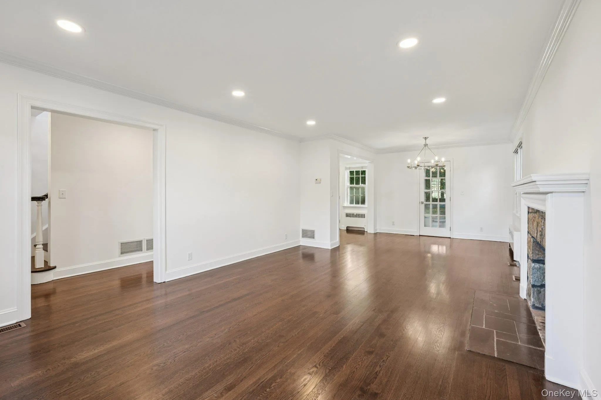 Unfurnished living room featuring crown molding, dark wood-style flooring, a fireplace, recessed lighting, and a chandelier Unfurnished living room featuring crown molding, dark wood-style flooring, a fireplace, recessed lighting, and a chandelier