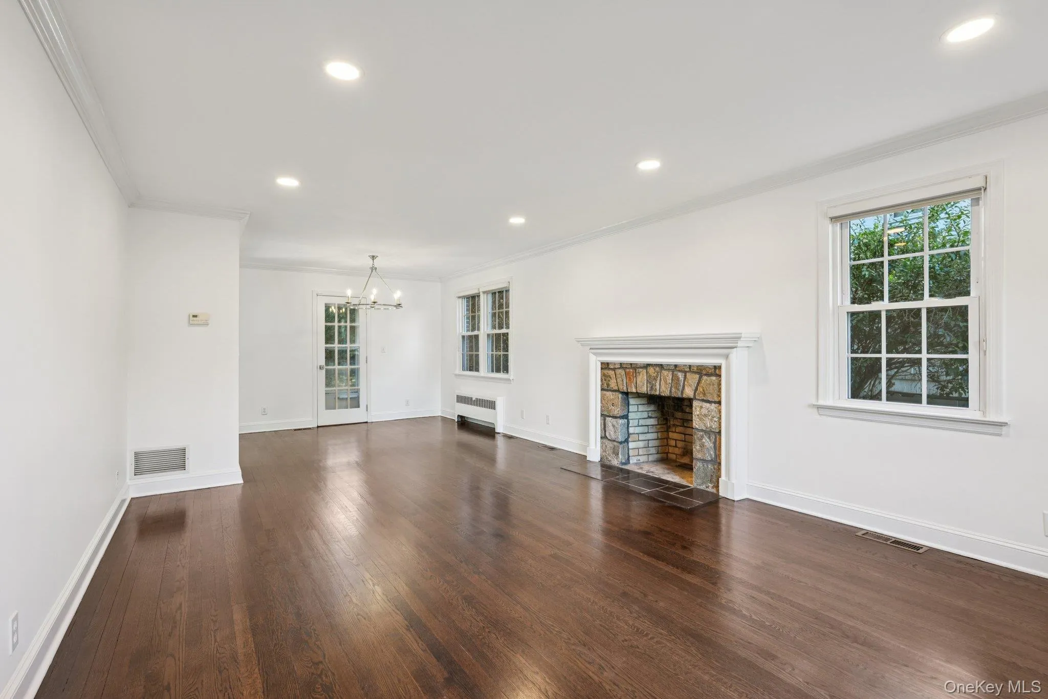 Unfurnished living room with crown molding, a fireplace, recessed lighting, dark wood-style floors, and healthy amount of natural light Unfurnished living room with crown molding, a fireplace, recessed lighting, dark wood-style floors, and healthy amount of natural light