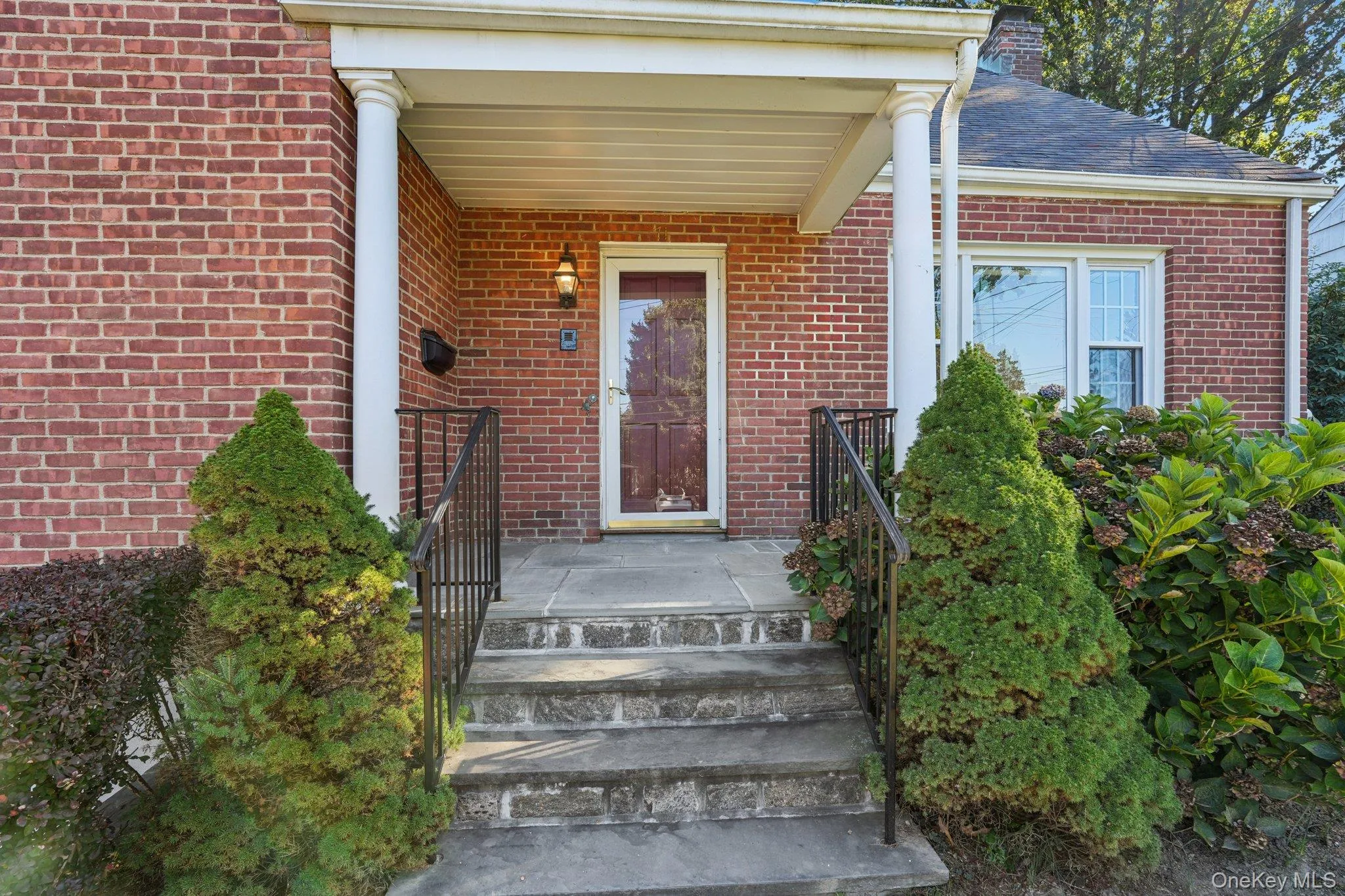 Property entrance with brick siding and a shingled roof Property entrance with brick siding and a shingled roof