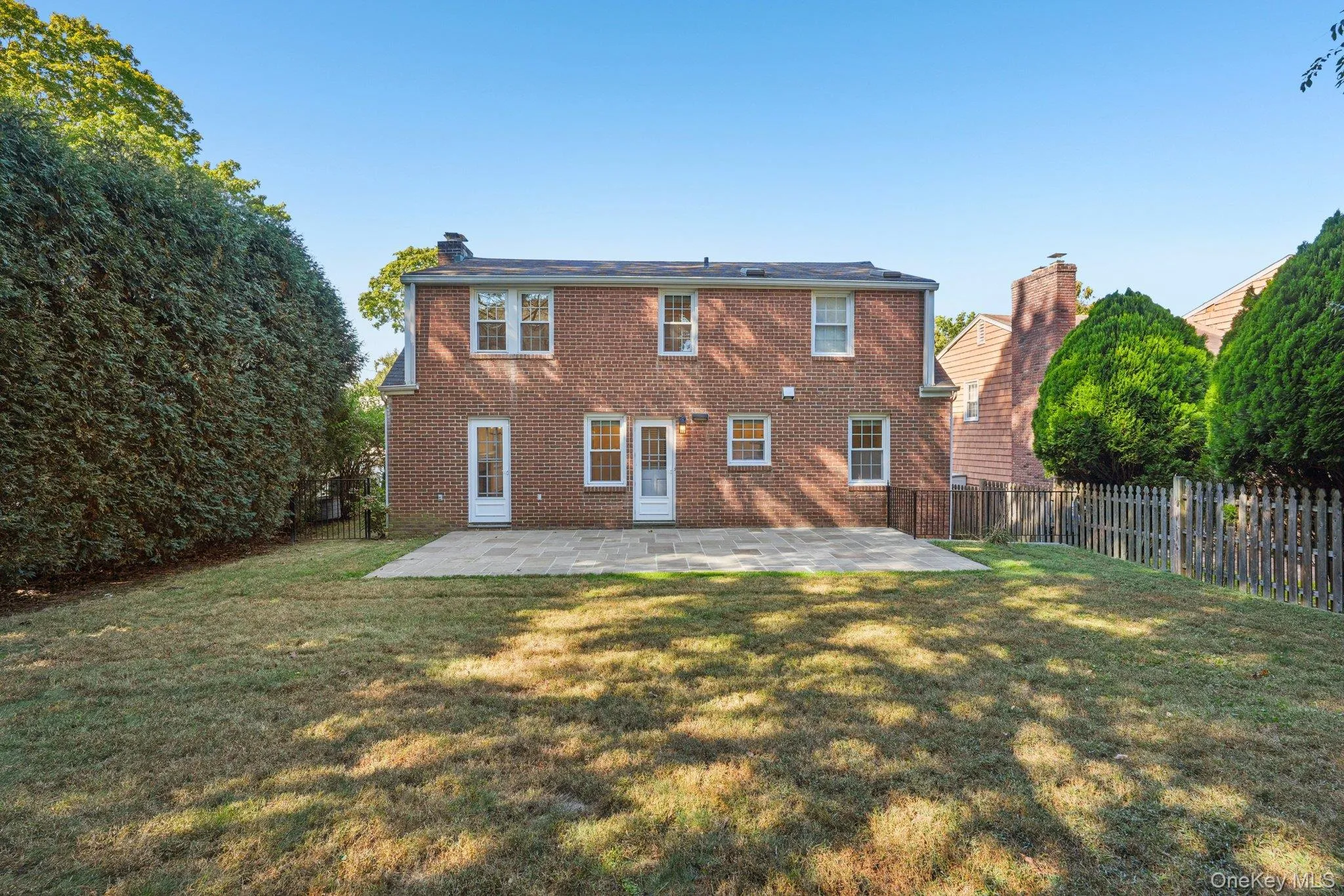 Rear view of property featuring a chimney, a patio, brick siding, and a fenced backyard Rear view of property featuring a chimney, a patio, brick siding, and a fenced backyard
