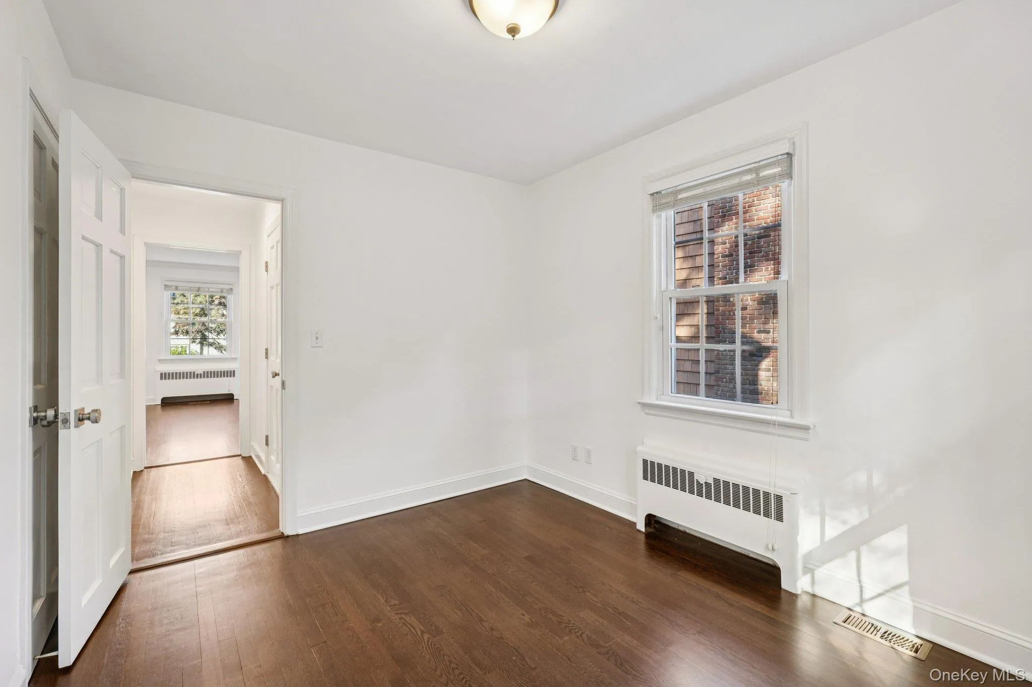 Empty room featuring radiator heating unit and dark wood-type flooring Empty room featuring radiator heating unit and dark wood-type flooring