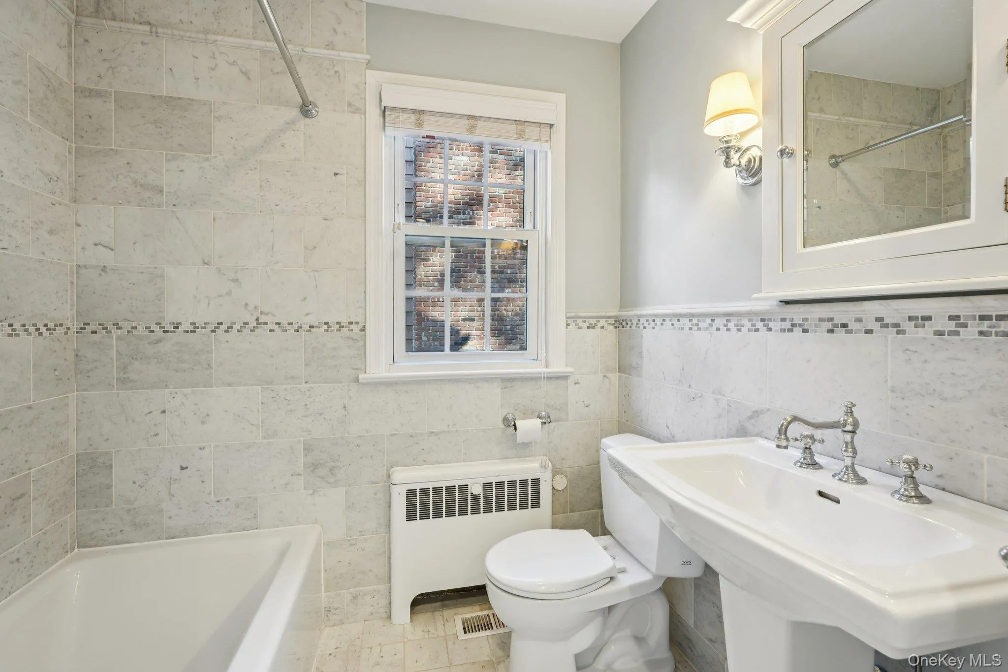 Bathroom featuring radiator, tile walls, washtub / shower combination, and a wainscoted wall Bathroom featuring radiator, tile walls, washtub / shower combination, and a wainscoted wall