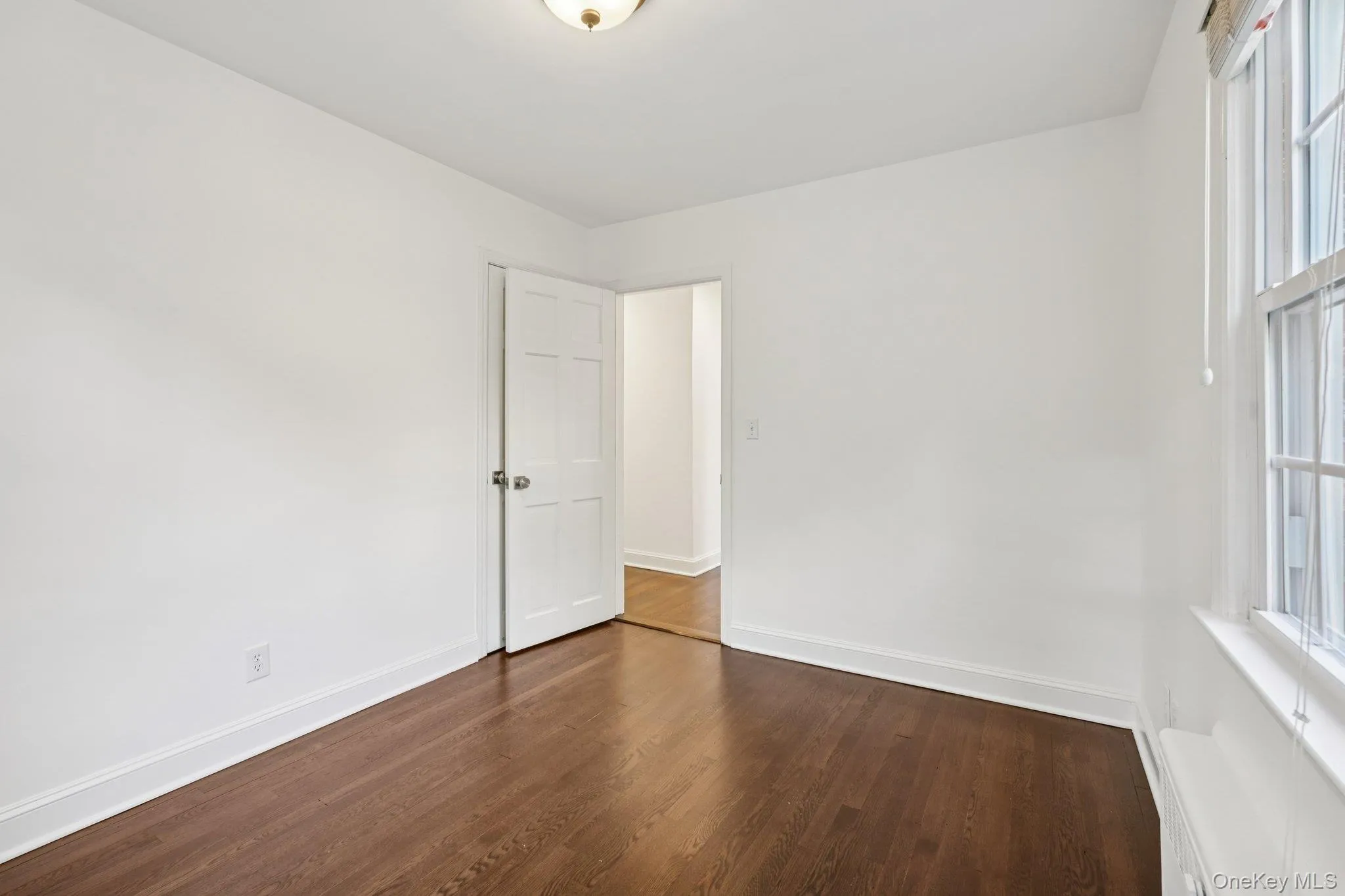 Spare room with dark wood-style flooring and baseboards Spare room with dark wood-style flooring and baseboards