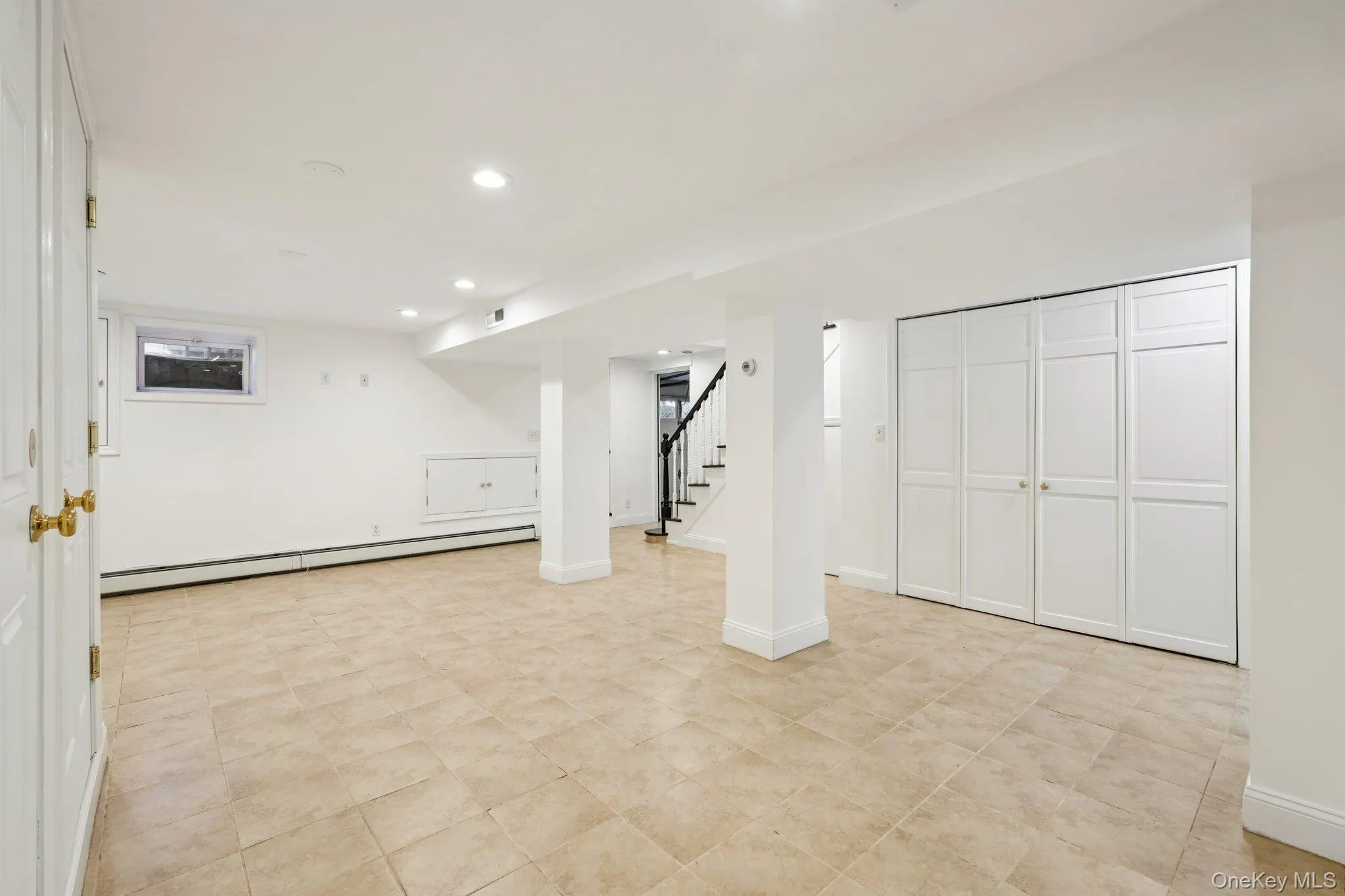 Finished basement featuring a baseboard radiator, recessed lighting, and stairs Finished basement featuring a baseboard radiator, recessed lighting, and stairs